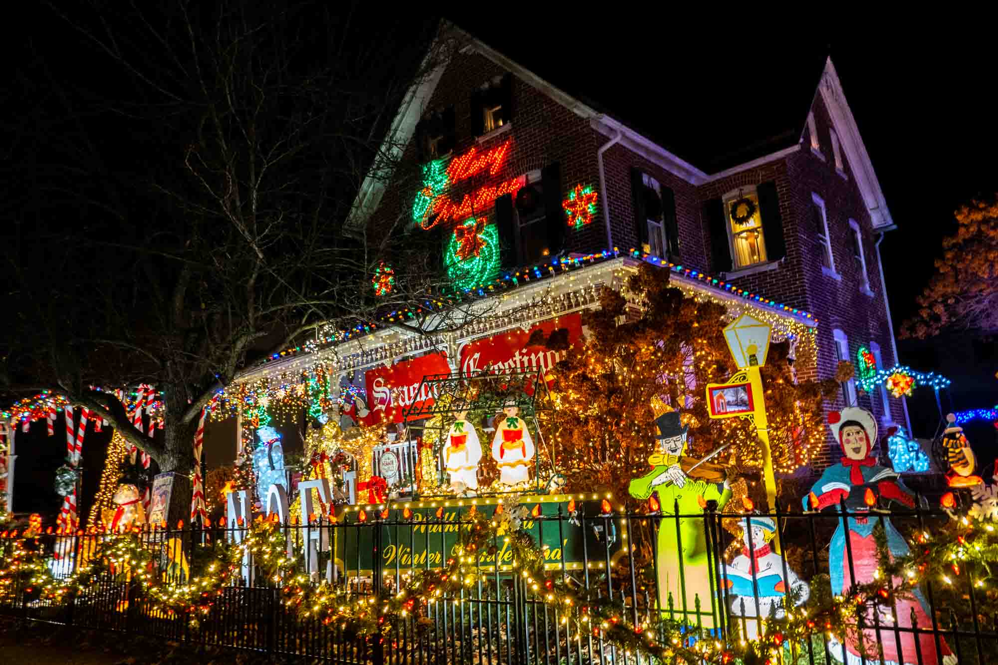 House covered in Christmas lights with numerous lights and holiday-themed  statues in the yard