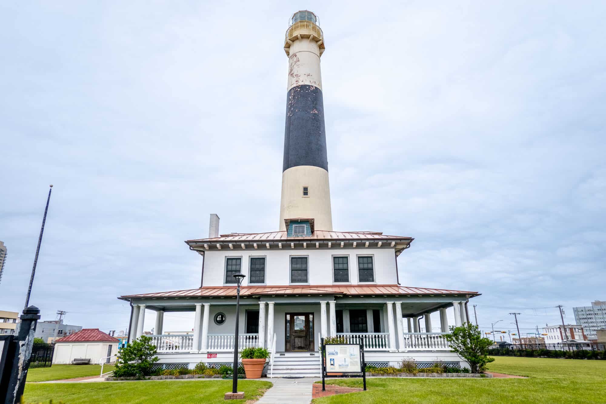 Black and white striped lighthouse towering over a 2-story building