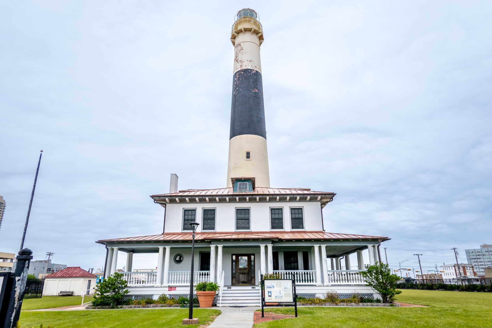 Black and white lighthouse with a 2-story build at its base.