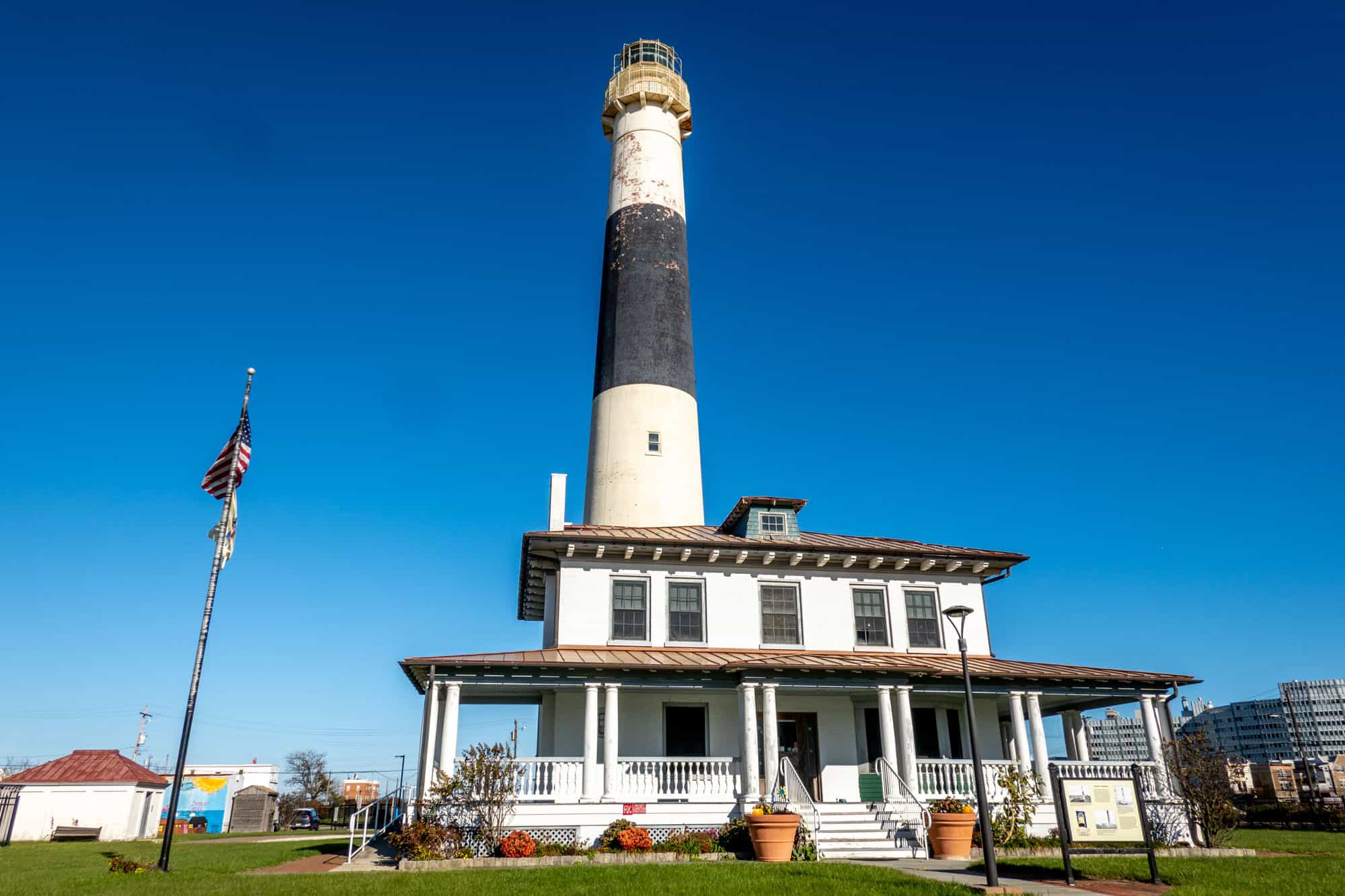 Black and white striped lighthouse over a 2-story building.