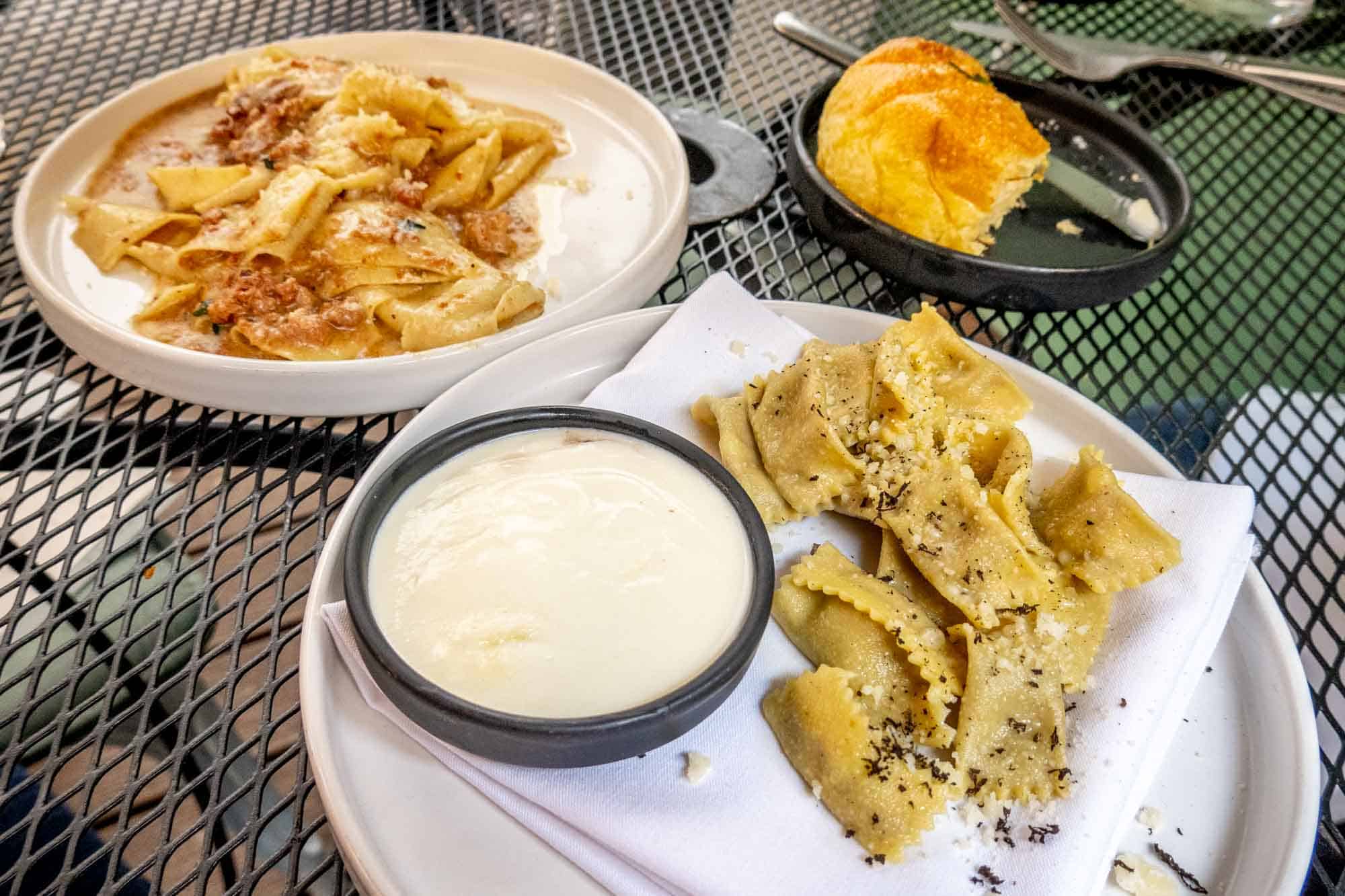 Plates of pastas and bread on a table.