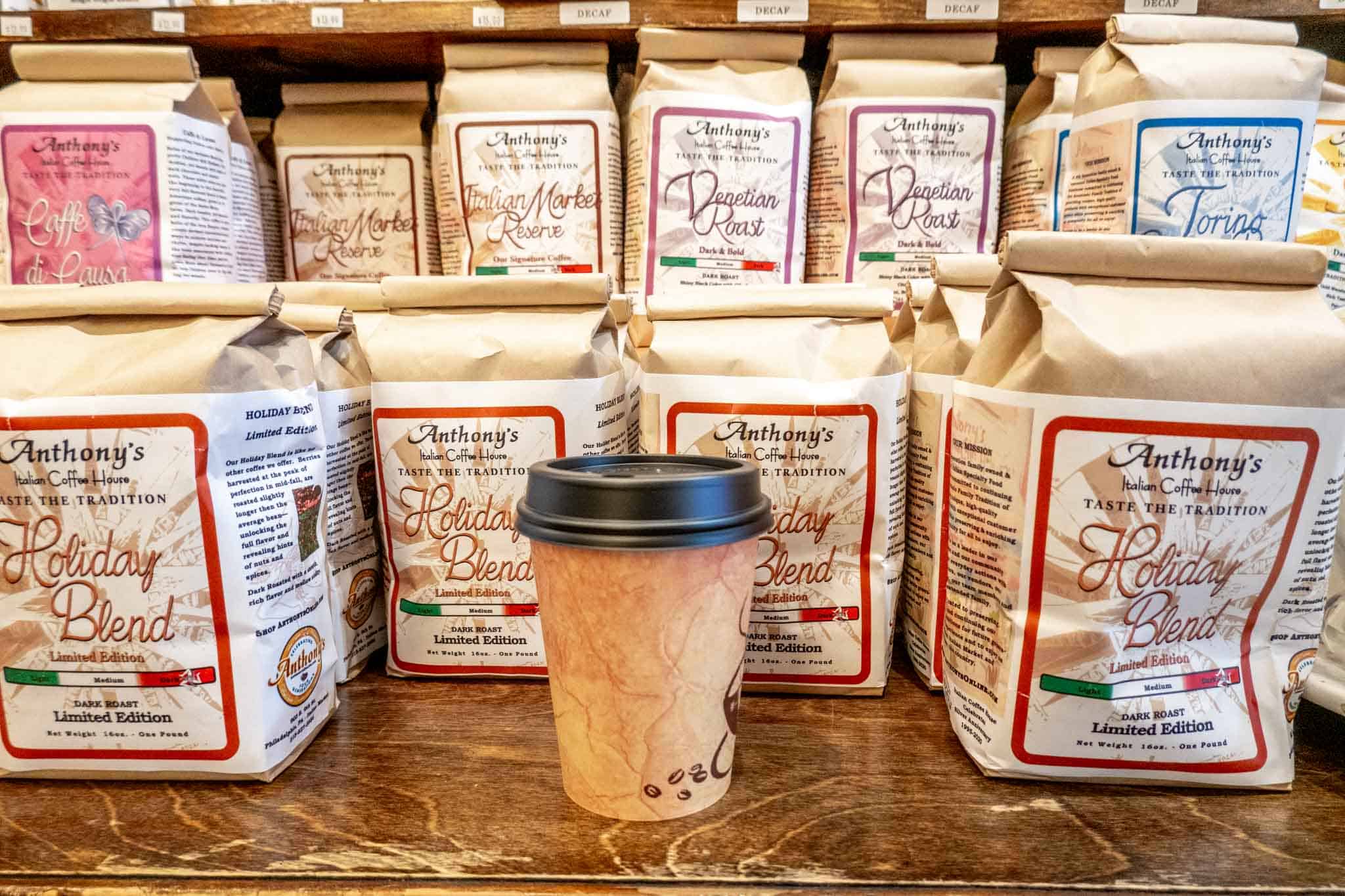 Cup on a counters beside bags of roasted coffee beans.