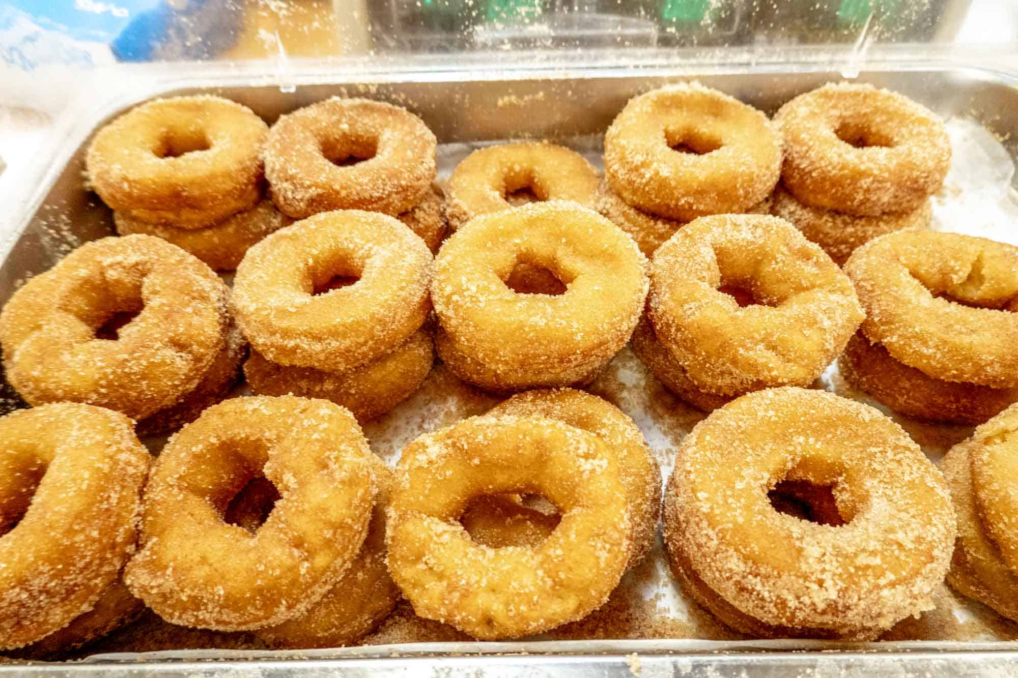 Tray full of dozens of sugar-coated donuts