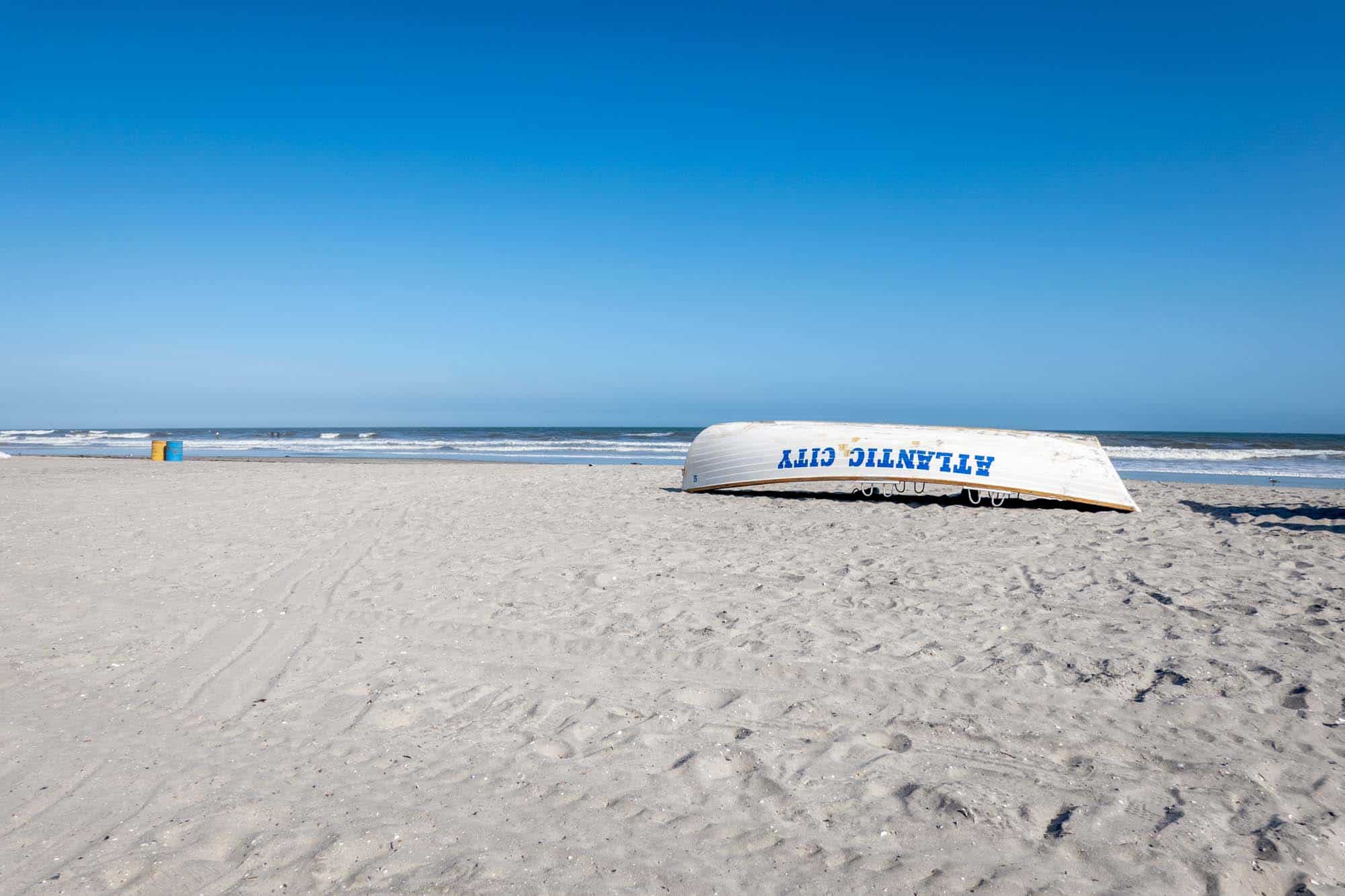 Empty beach with lifeboat that says "Atlantic City" turned upside down.