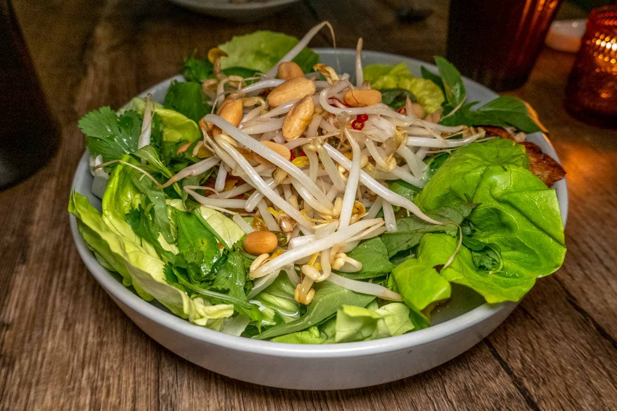 Salad of lettuce, bean sprouts and peanuts in white bowl at Mawn restaurant