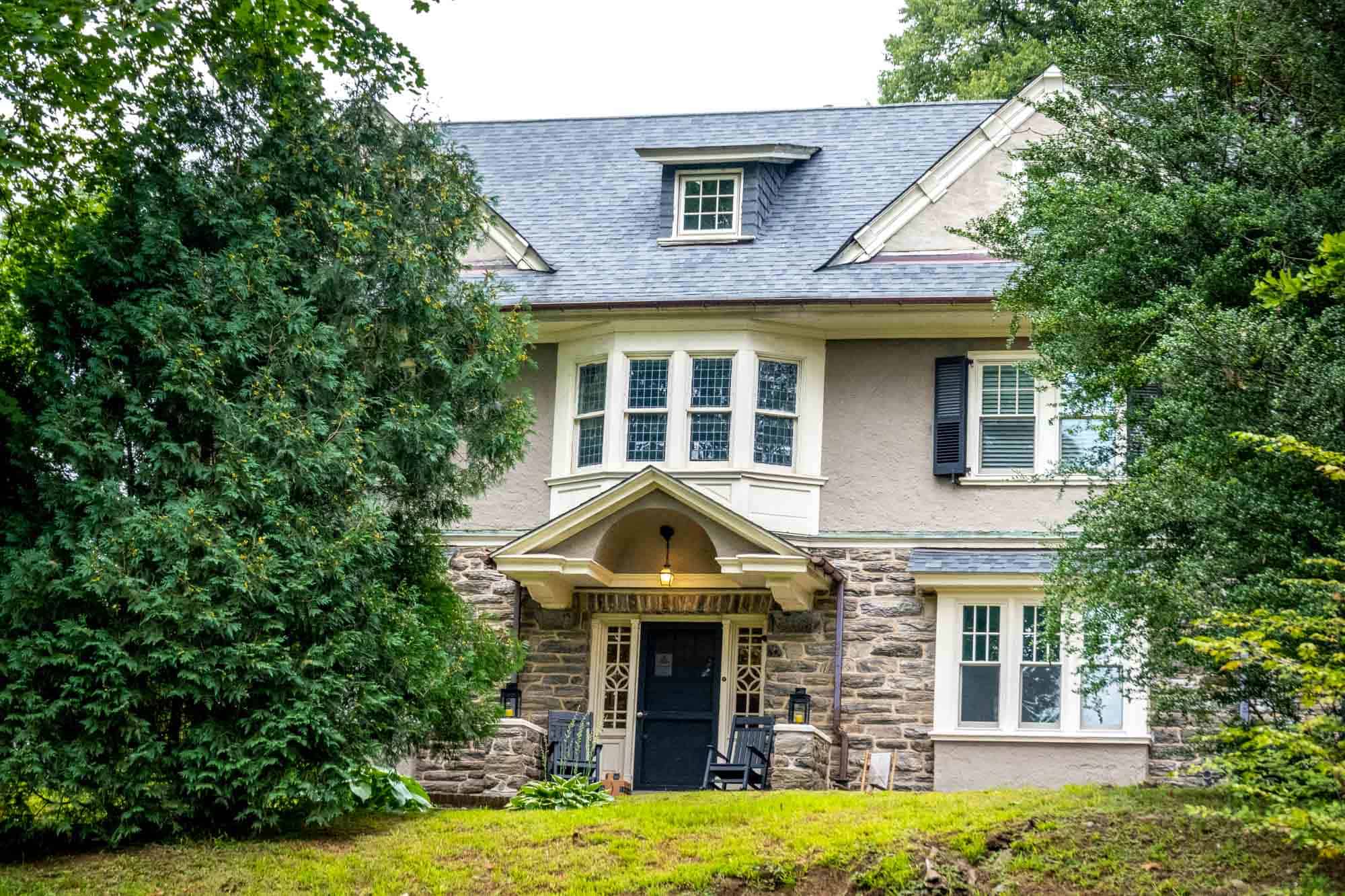 Large house made of stone and stucco with a bay window.