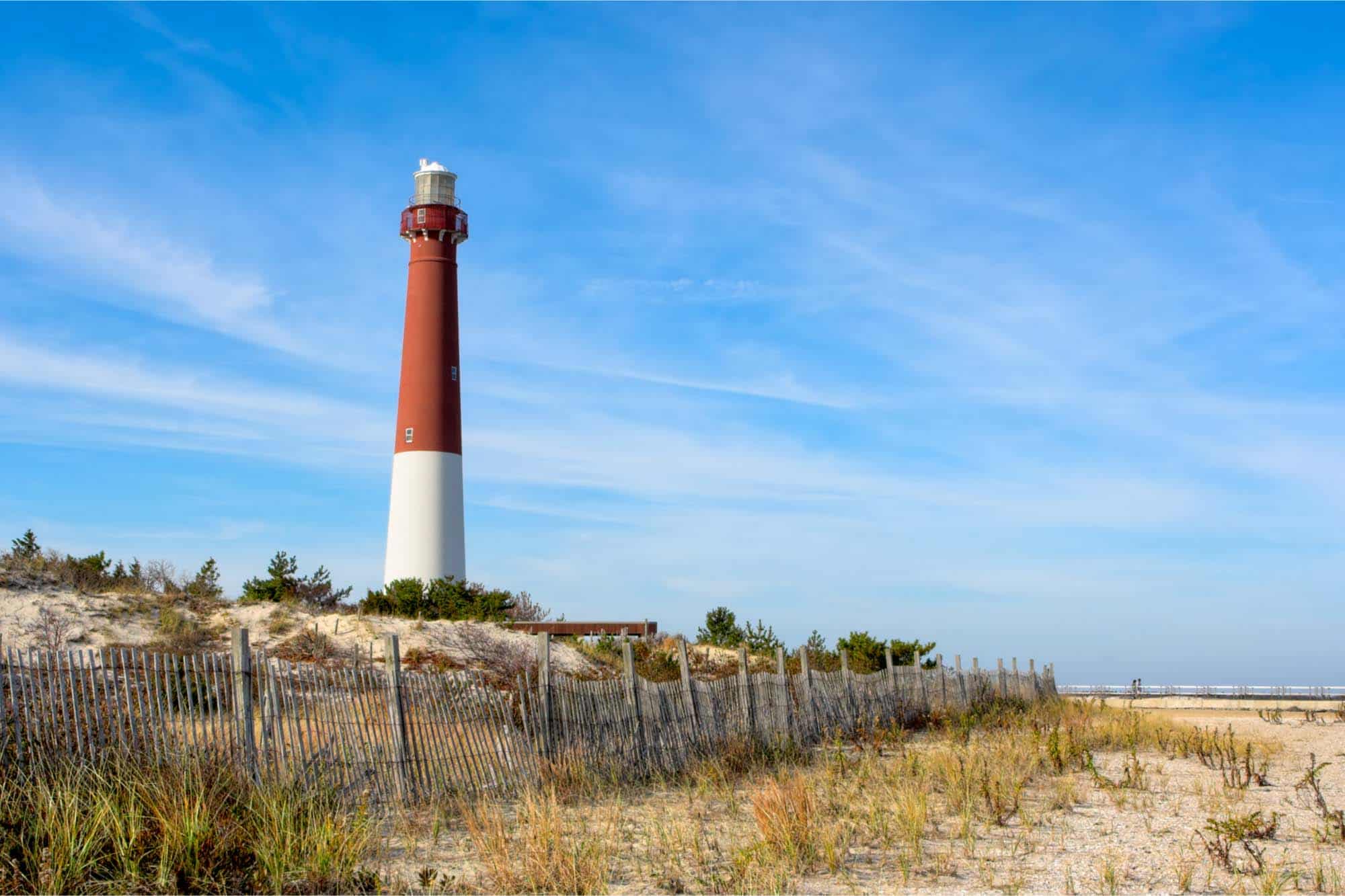 Red and white lighthouse above a sandy beach