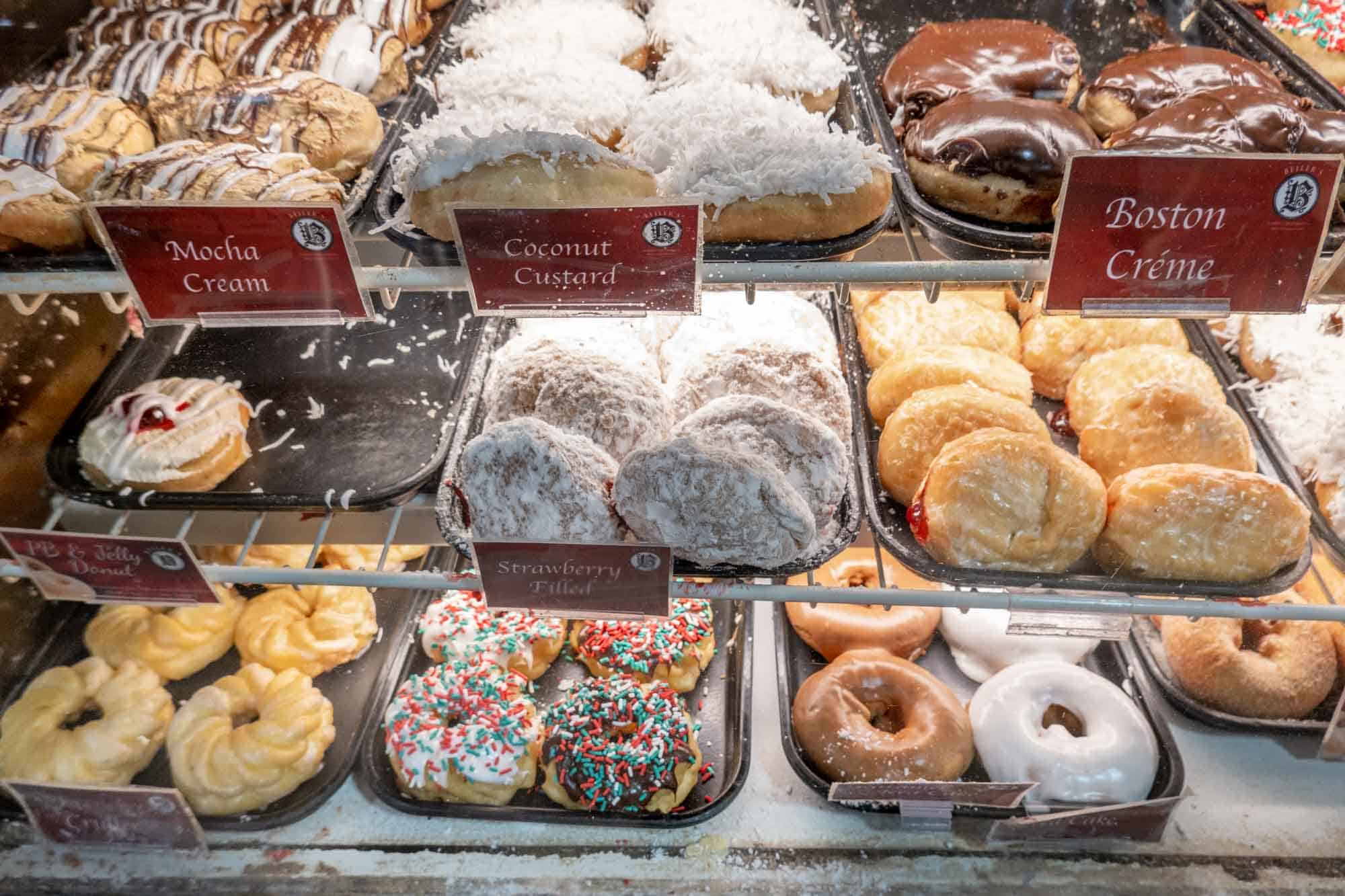 Display case filled with trays of glazed and filled donuts.