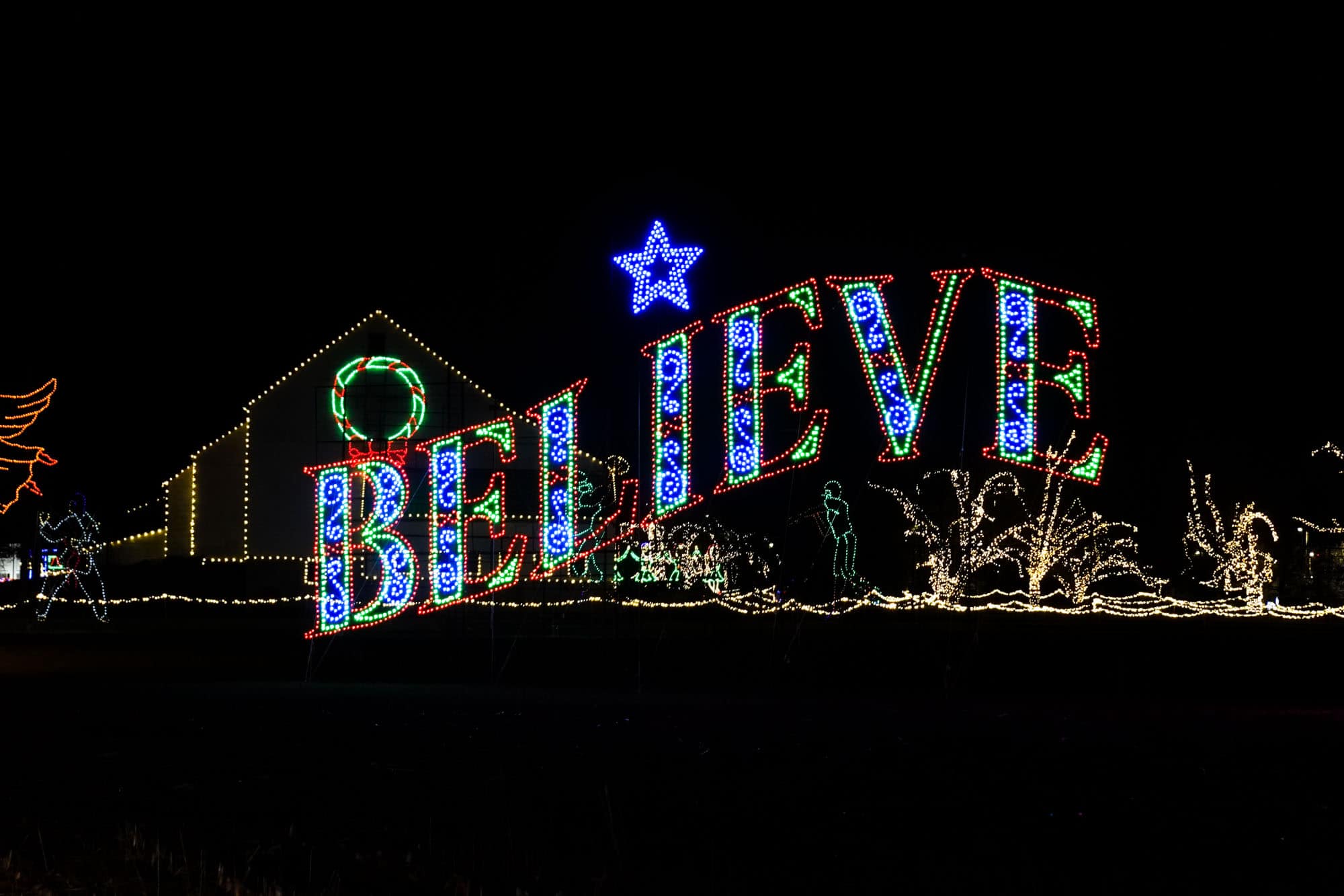 Blue and red holiday lights spelling out "Believe."