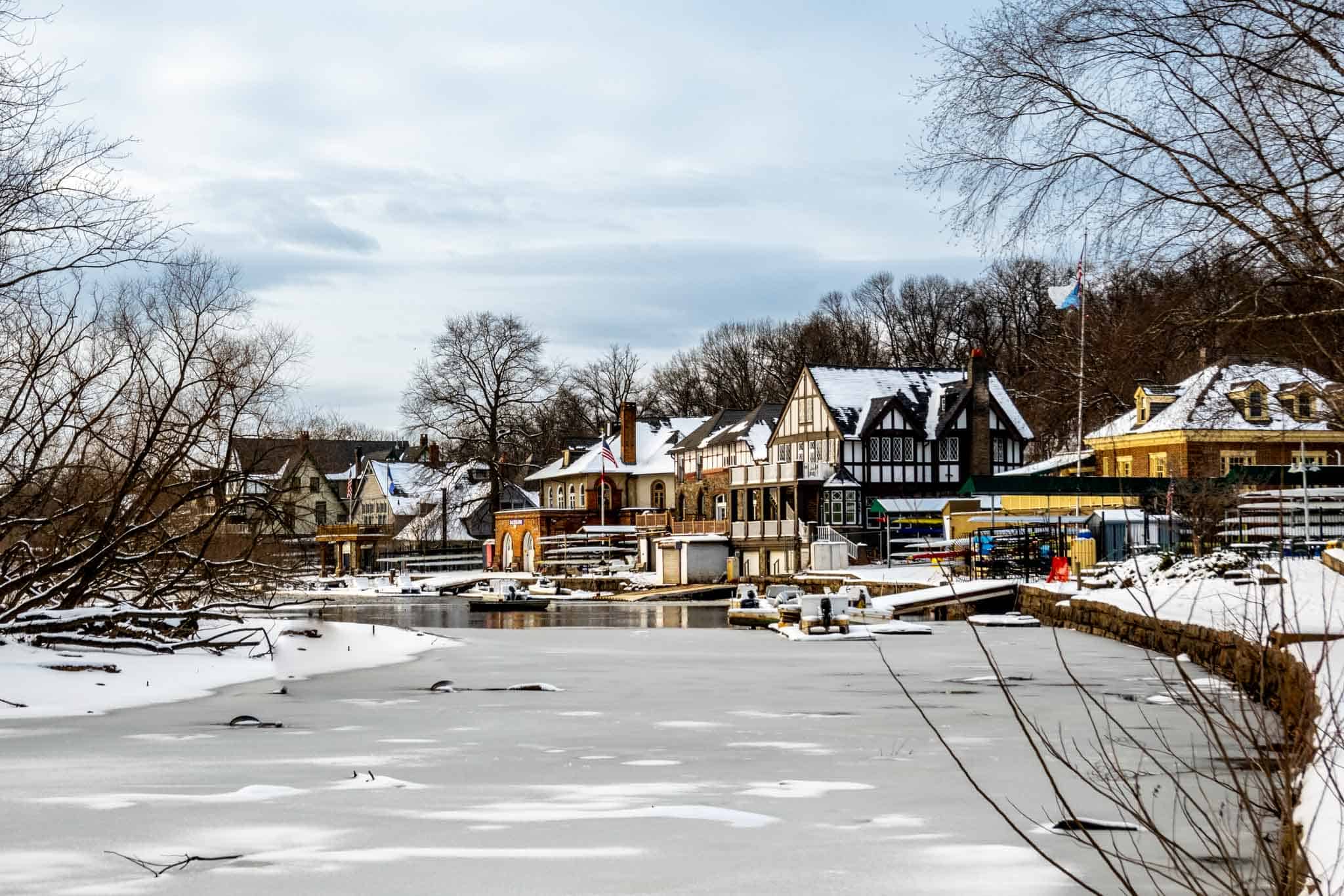 Buildings covered in snow on the edge of an icy river.