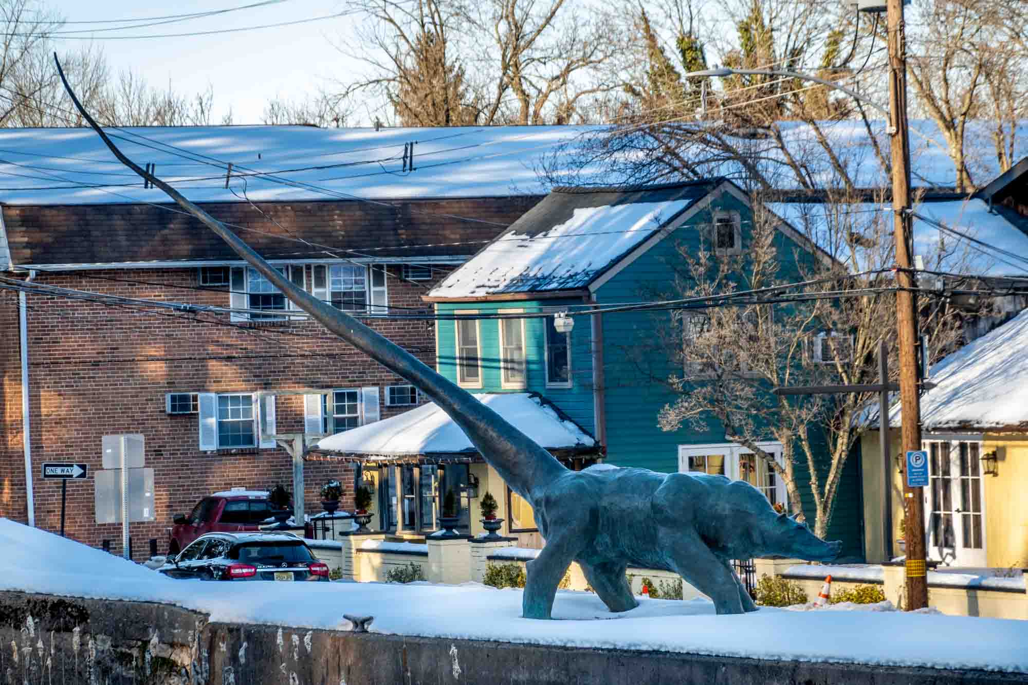 Green sculpture of a dog-like creature with a long tail on a snowy day