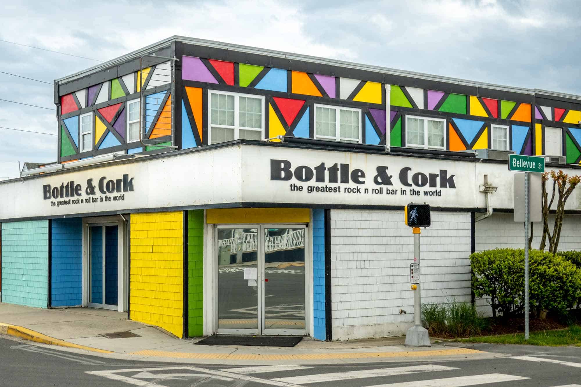Building with primary color geometric designs and a sign: "Bottle & Cork, the greatest rock n roll bar in the world"