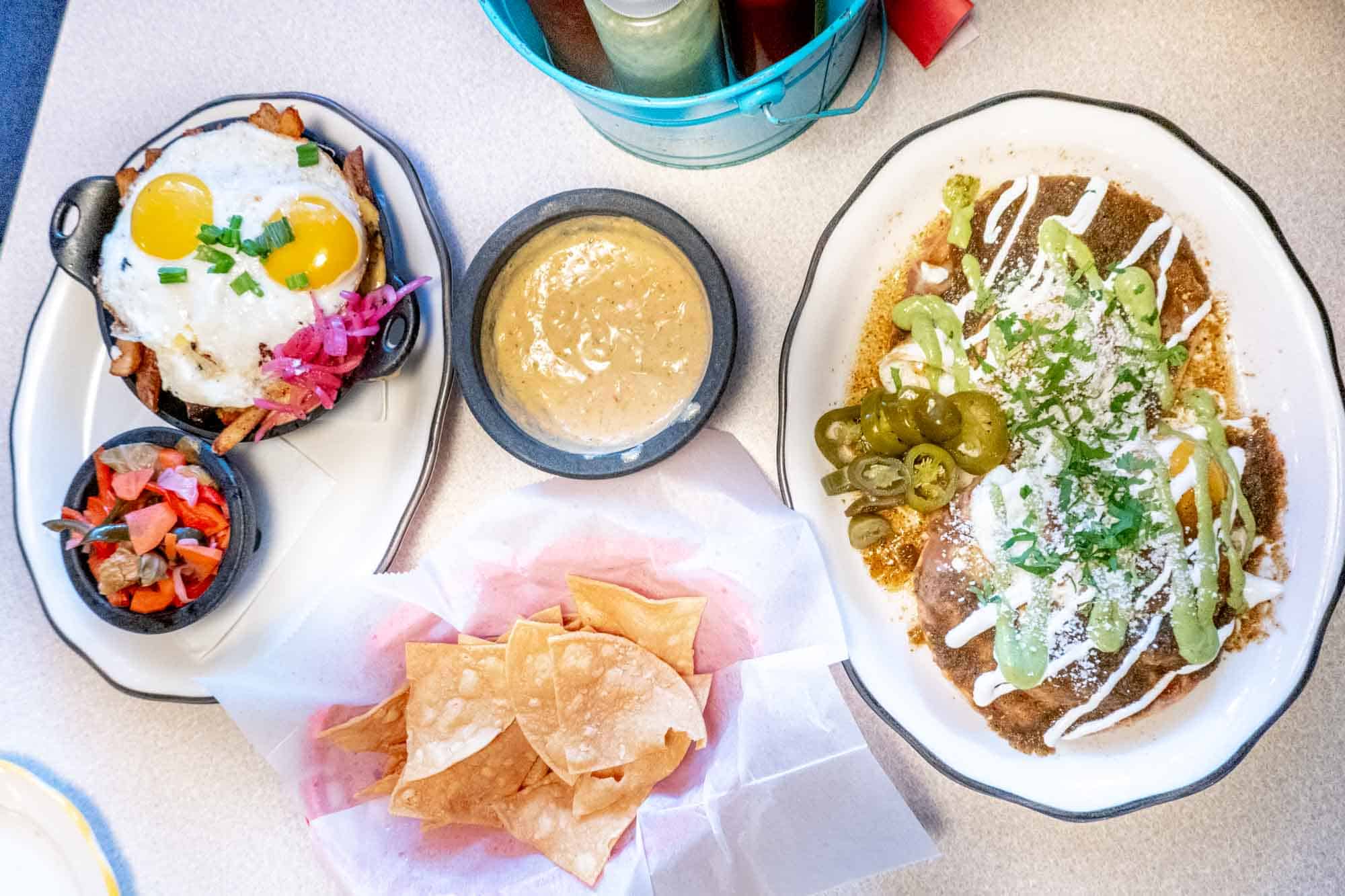 Tortilla chips, queso, salsa, and more food on a table at a Mexican restaurant.