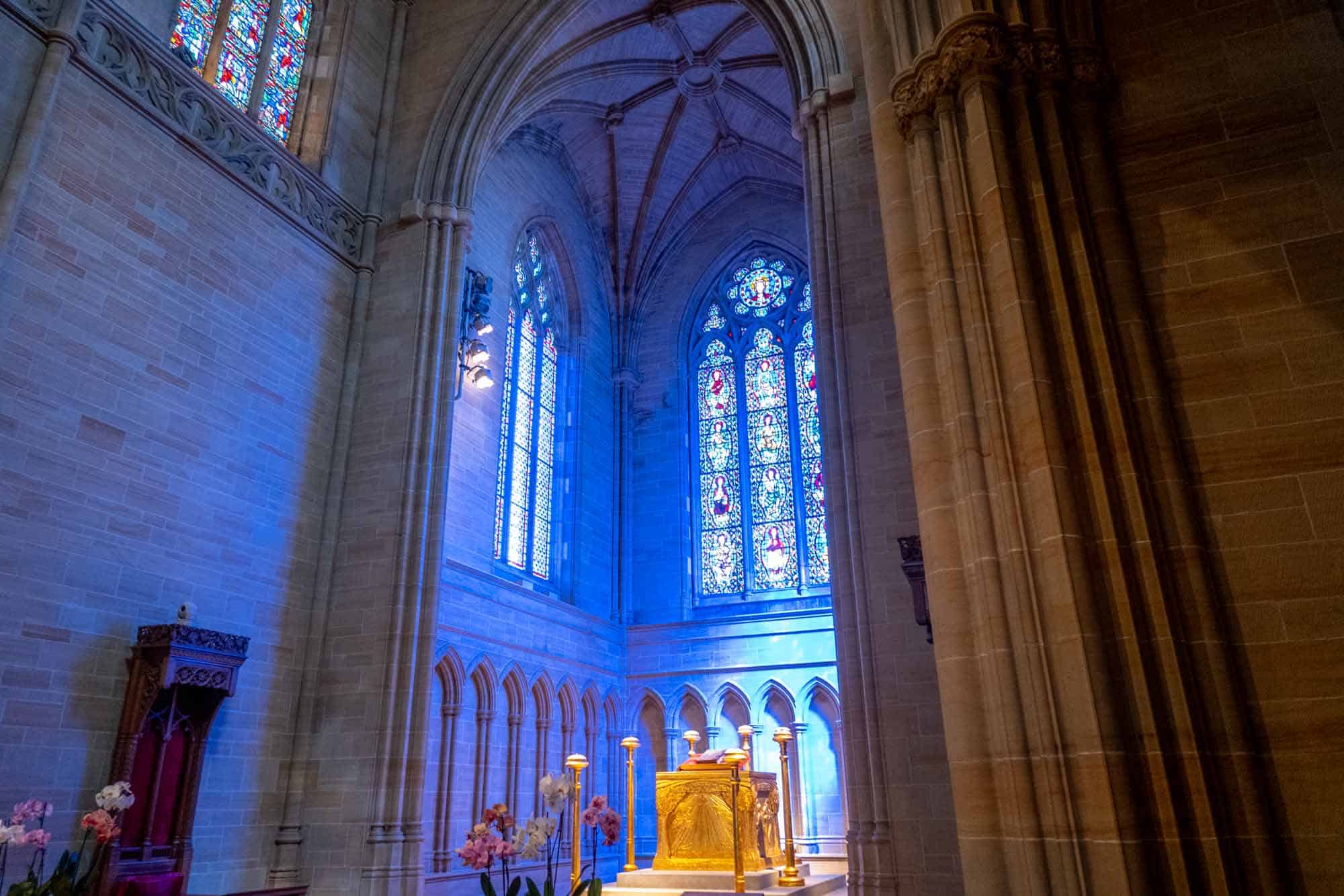 Light streams through stained-glass windows over an altar in a cathedral sanctuary.