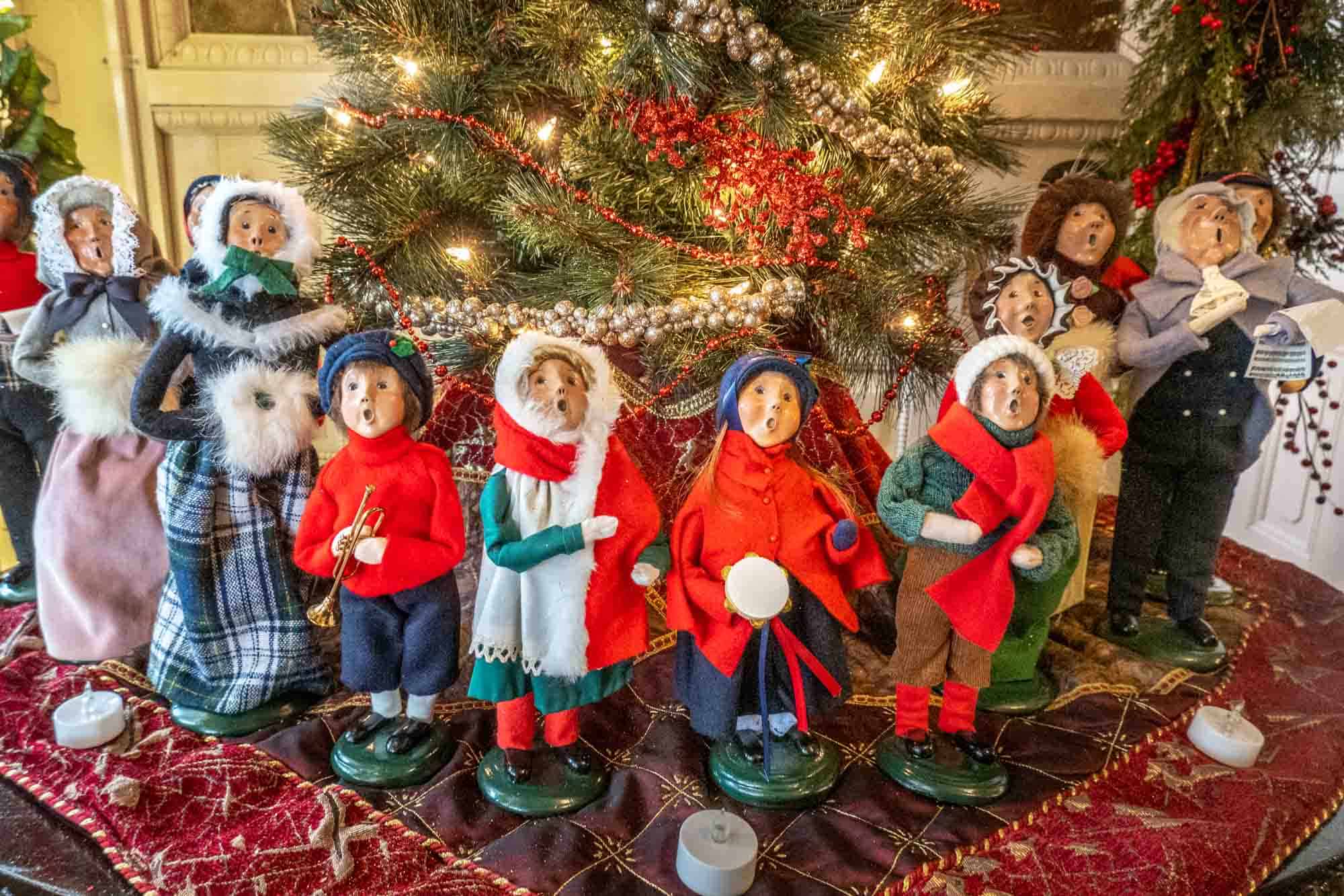 Carved wooden figurines dressed in Christmas and winter clothing.