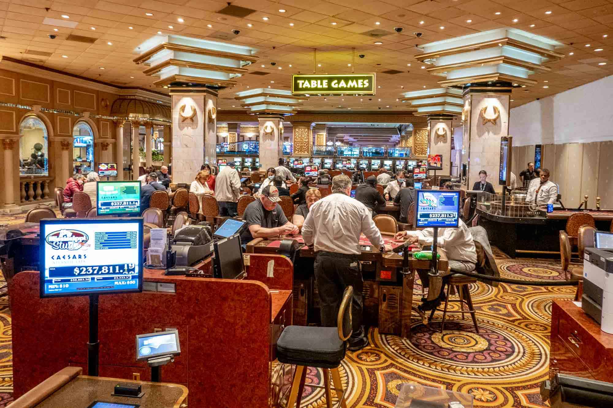 People sitting at game tables in a casino under a sign for "table games"