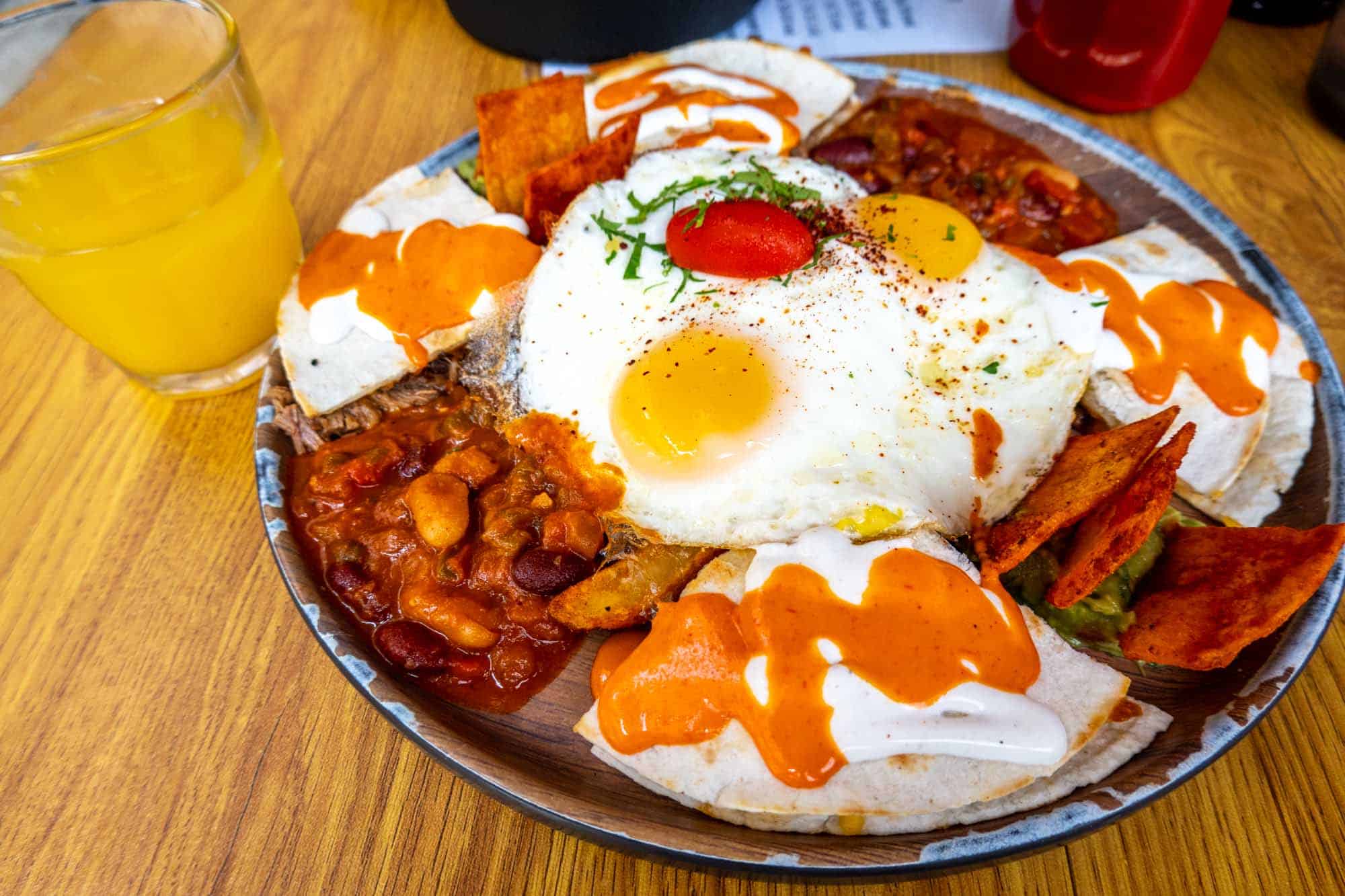 Plate with eggs and beans beside a glass of orange juice.