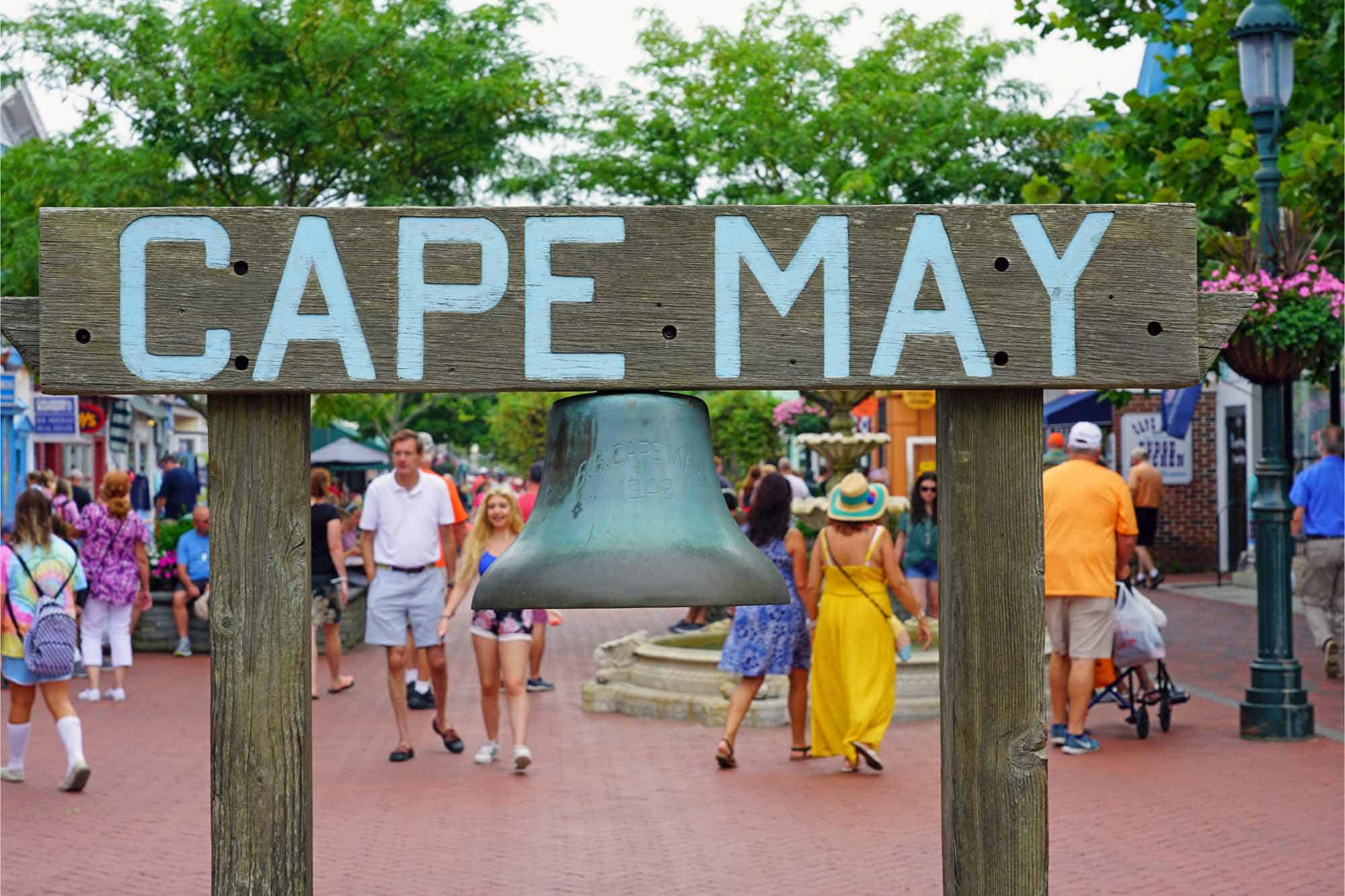 Cape May sign with bell and people walking in the background
