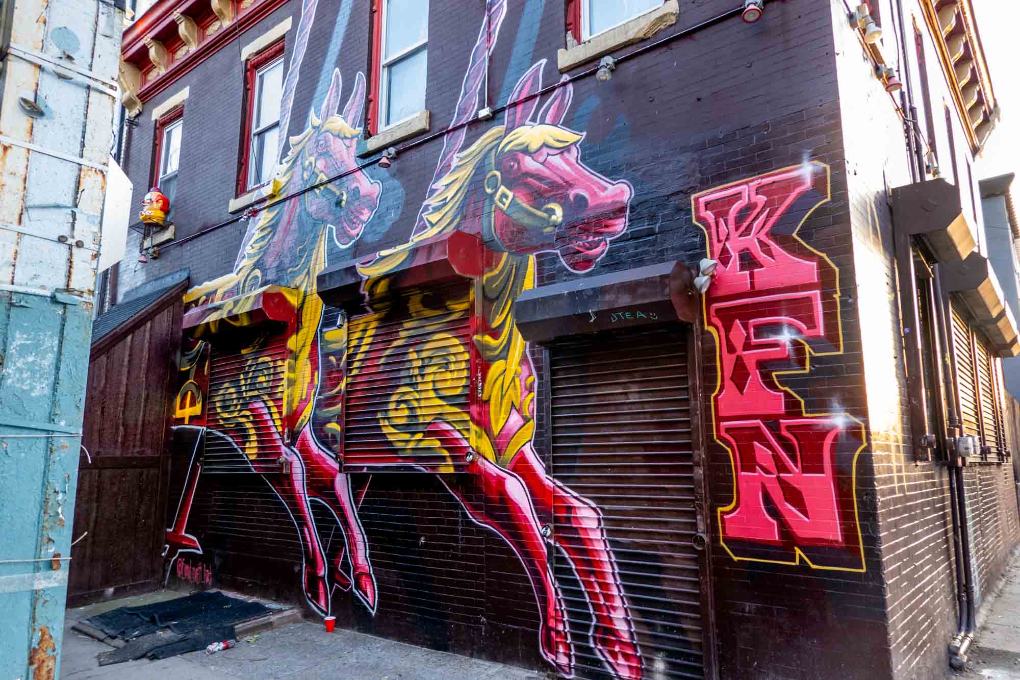 Pink and yellow carousel horses painted on building with initials KFN