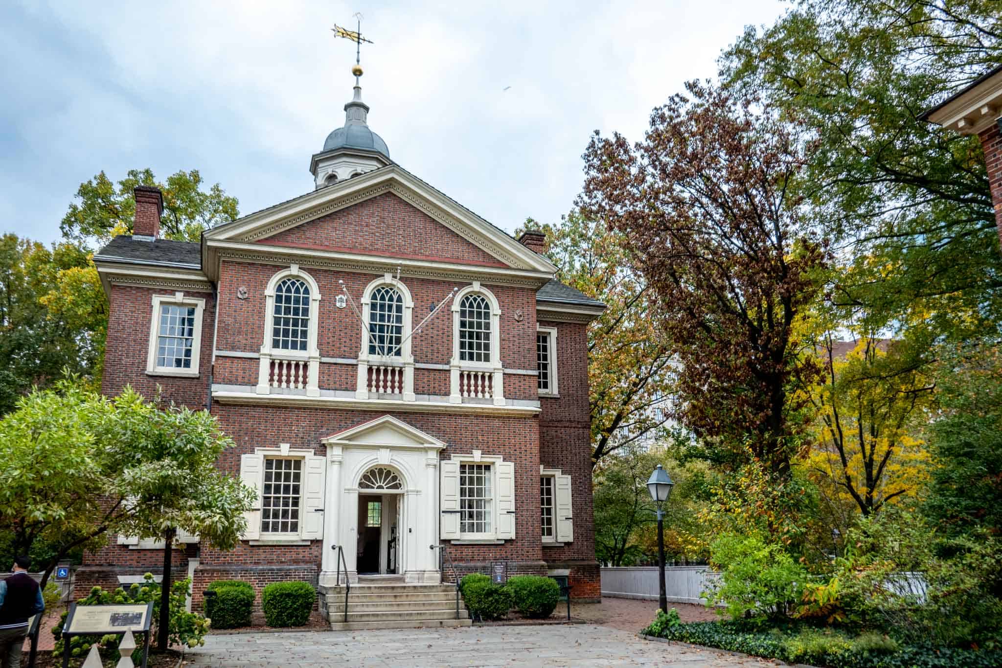 Red brick building with a cupola surrounded by trees