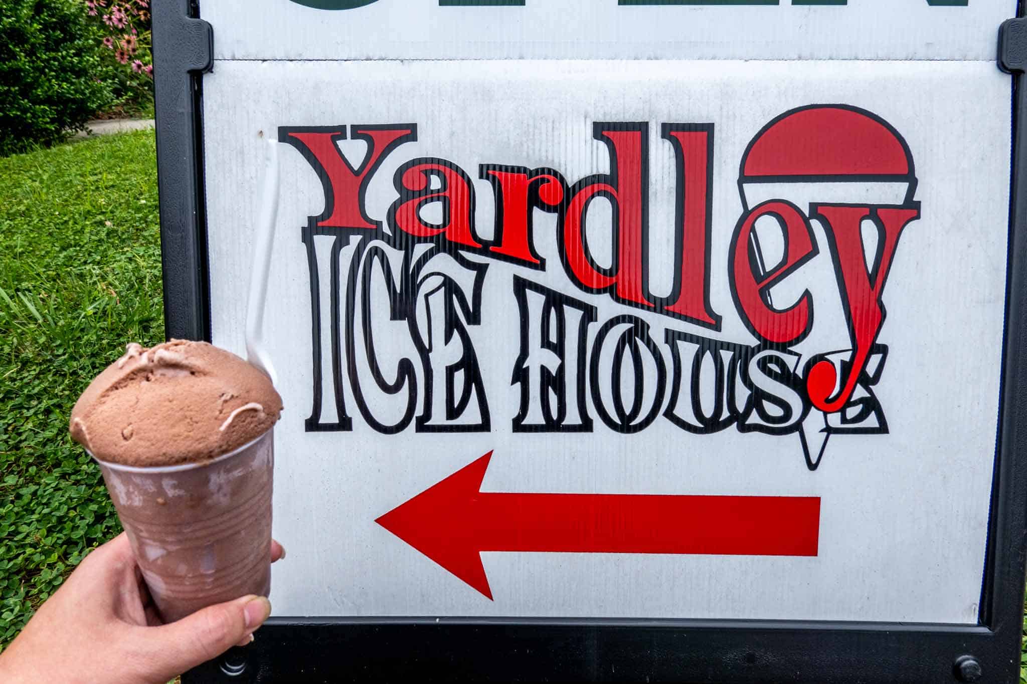 Hand holding a cup of water ice beside a sign for Yardley Ice House.