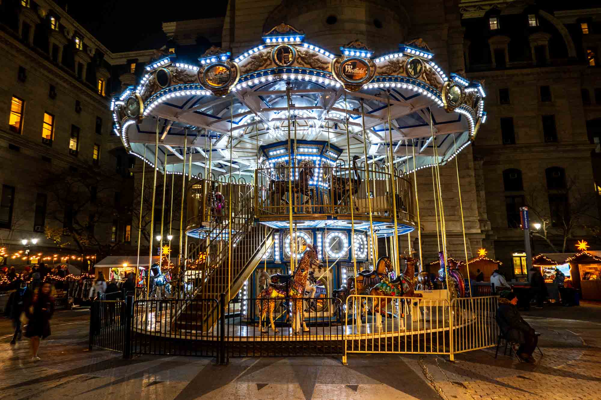 Double-decker carousel lit with blue and white lights at night
