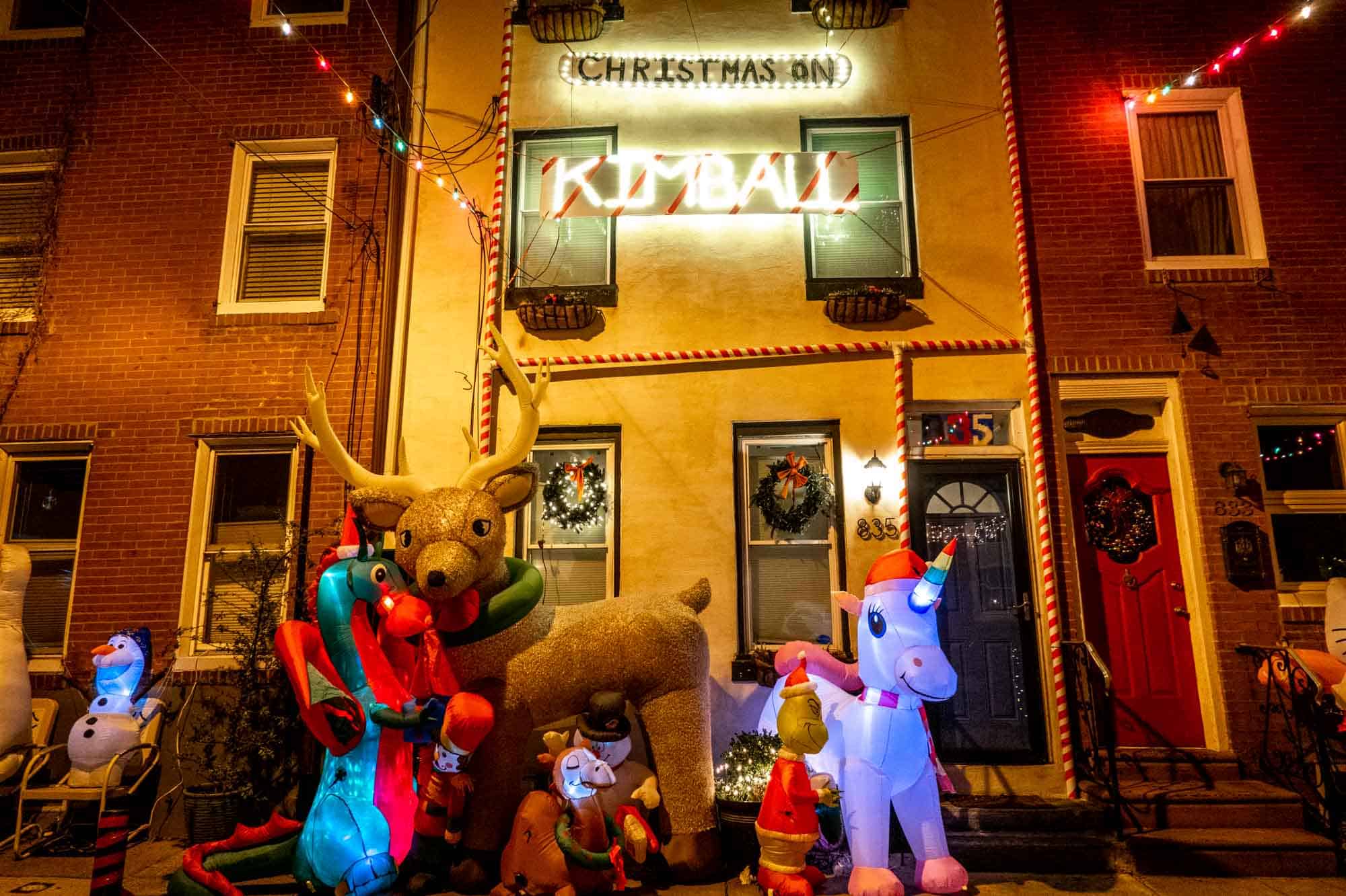 Inflatable characters in front of a lit sign for Christmas on Kimball.