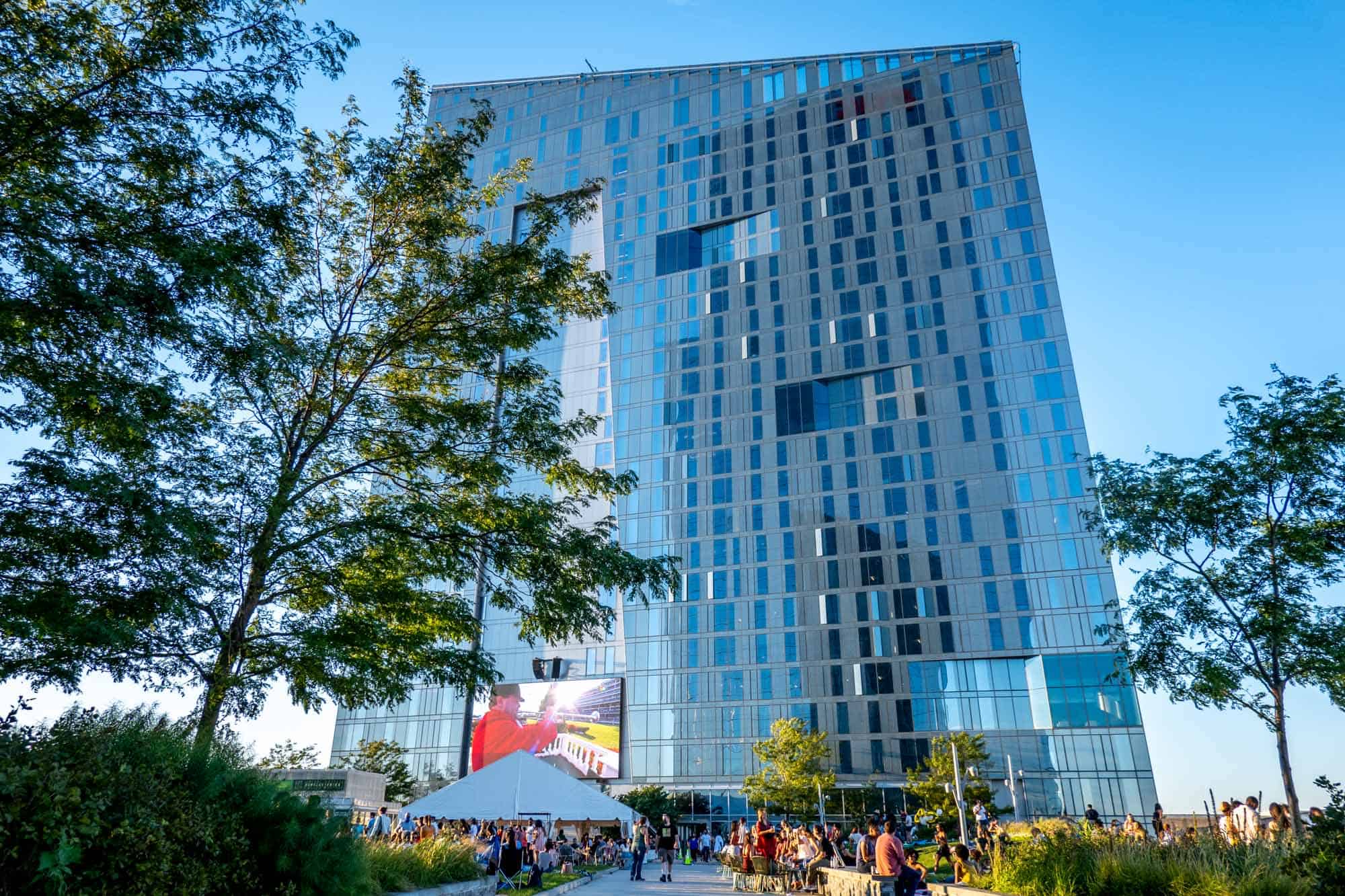 Skyscraper towering above a park filled with people