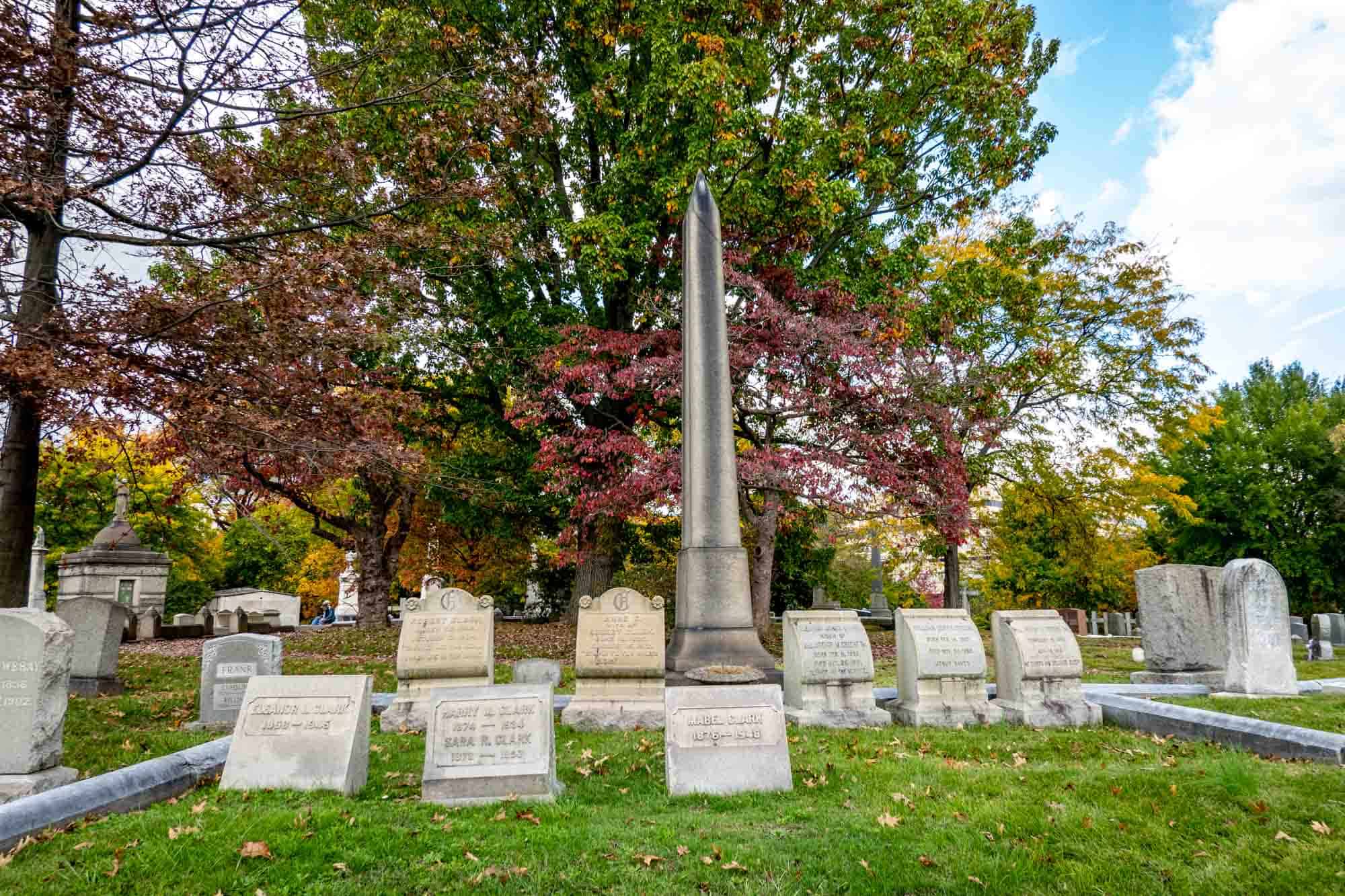 Row of stone headstones in a family plot with a large obelisk in the center