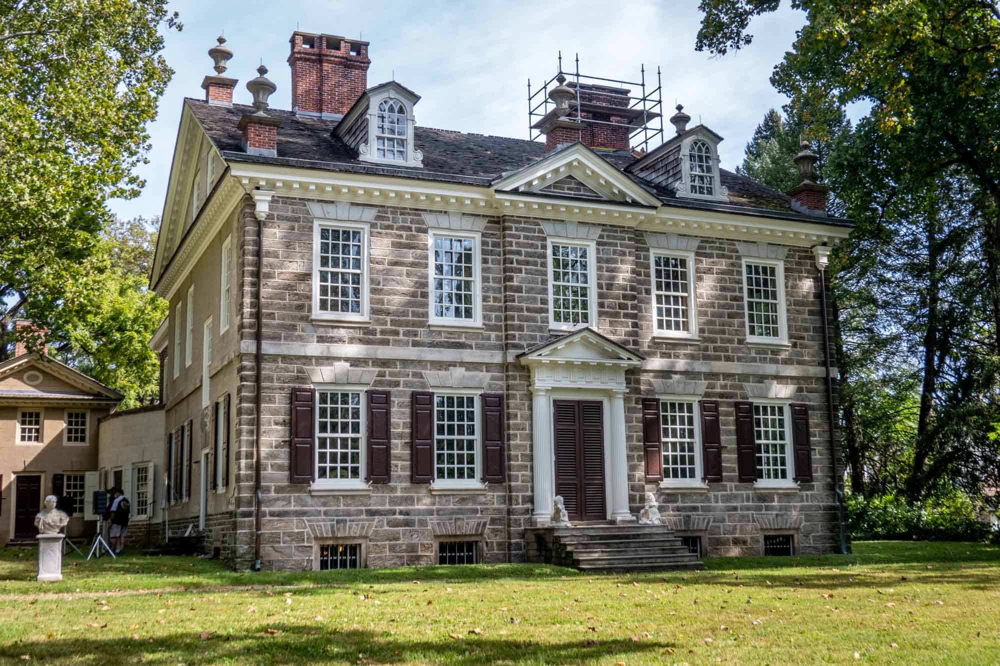 Two-story historic stone house with lots of windows.