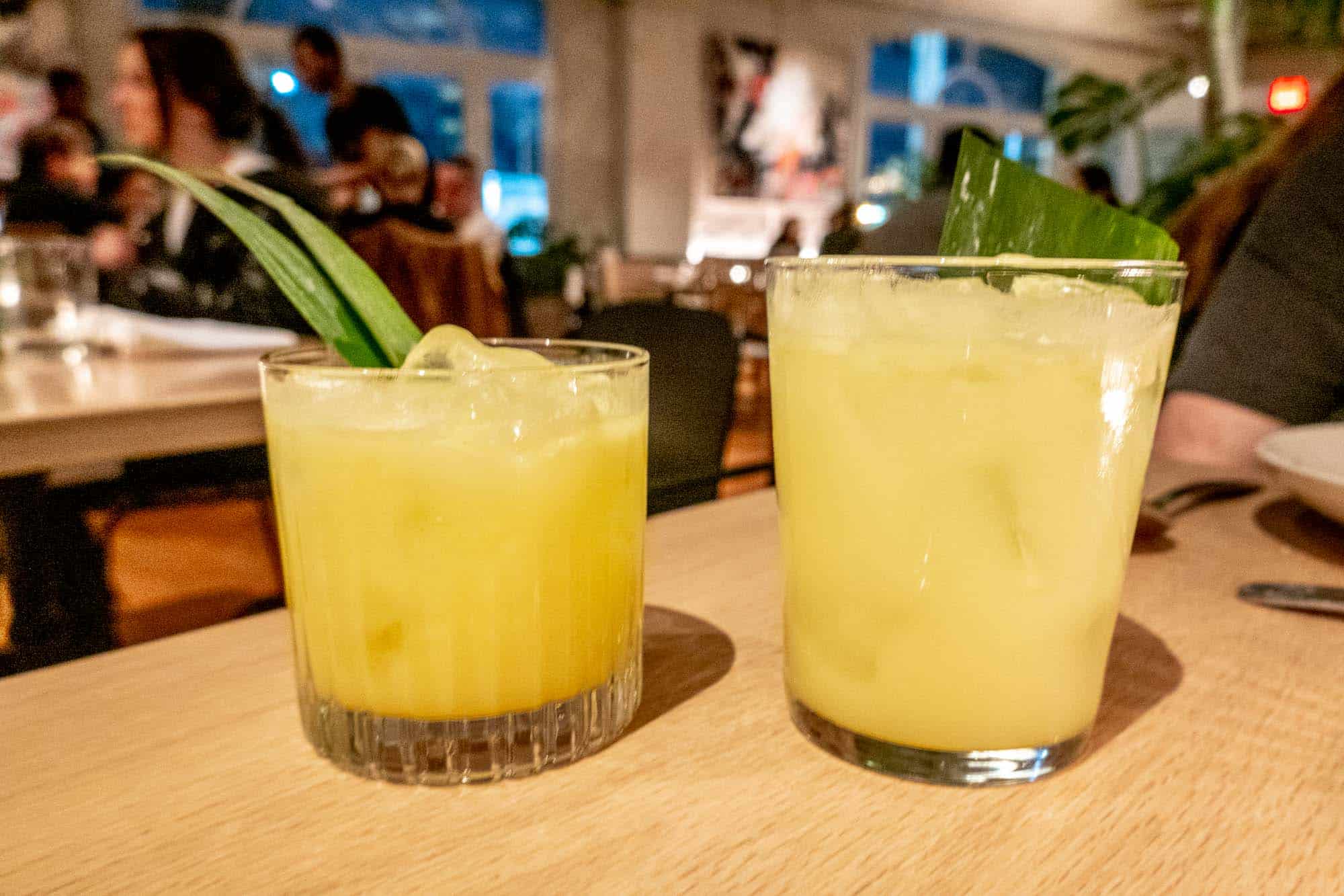 Two yellow cocktails in rocks glasses on a table.