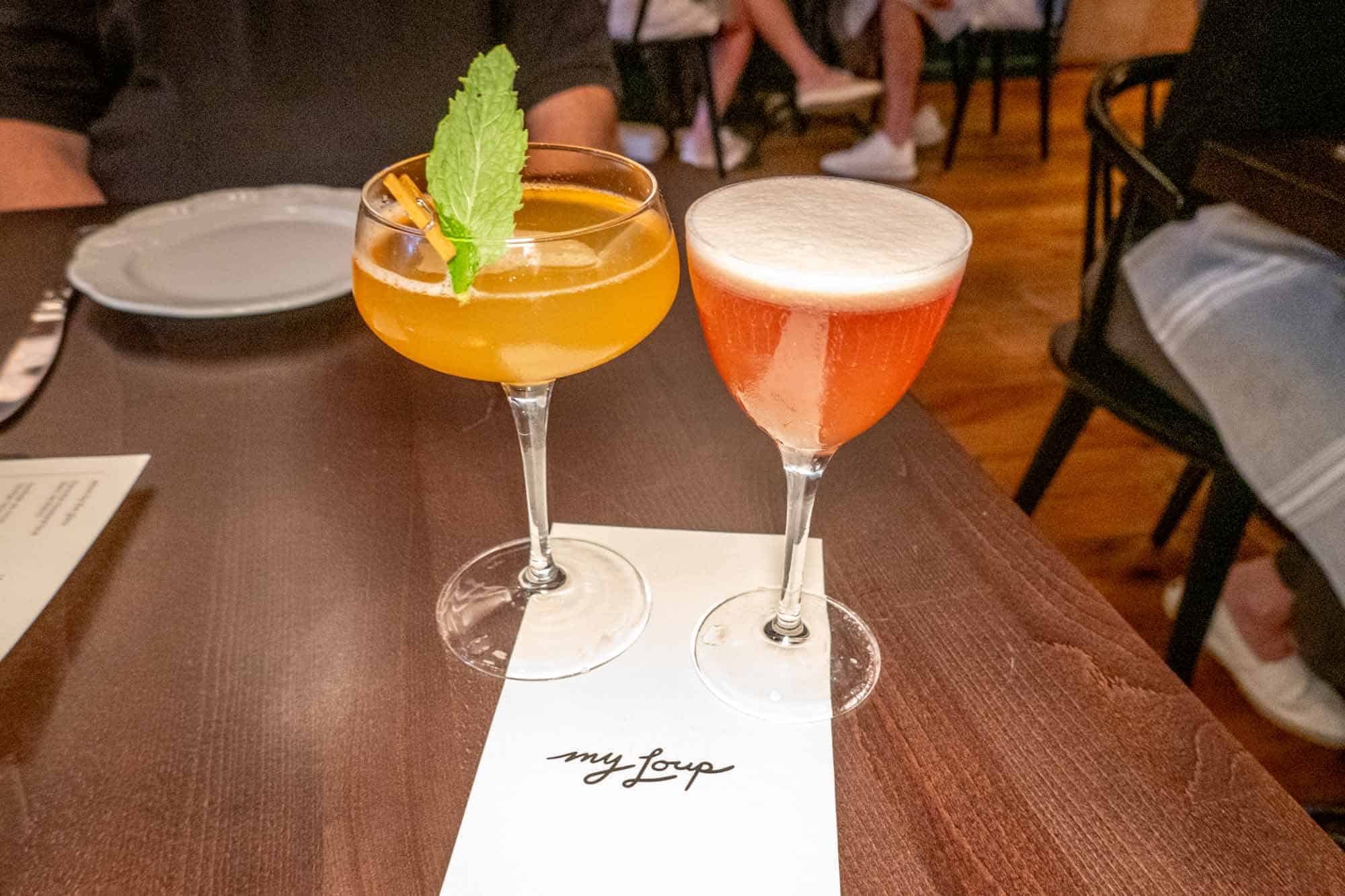Two cocktail glasses resting on white menu that says "My Loup"