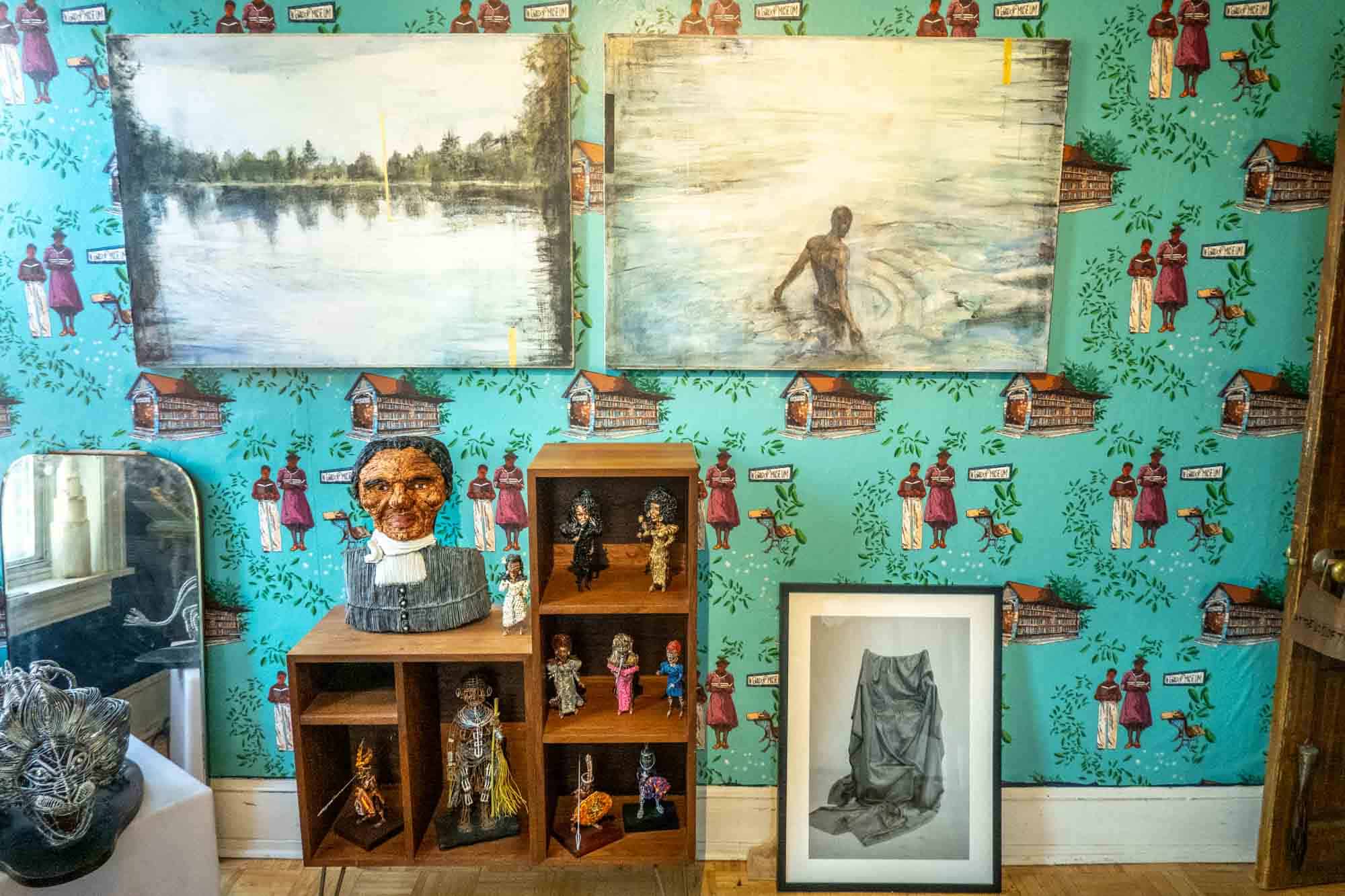 Paintings and wire sculptures displayed in a bedroom in a house museum.