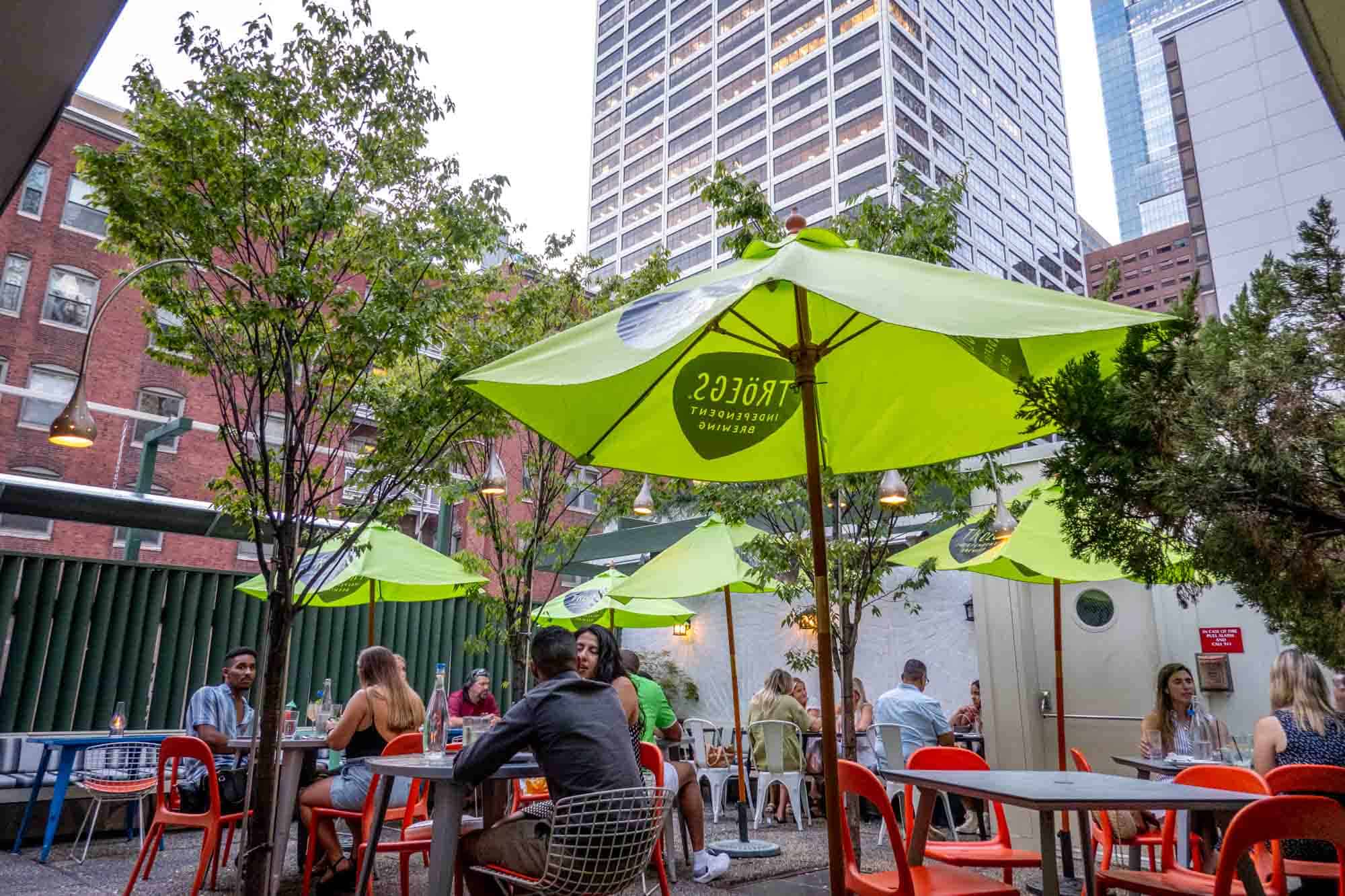 People seated at tables under bright green umbrellas.