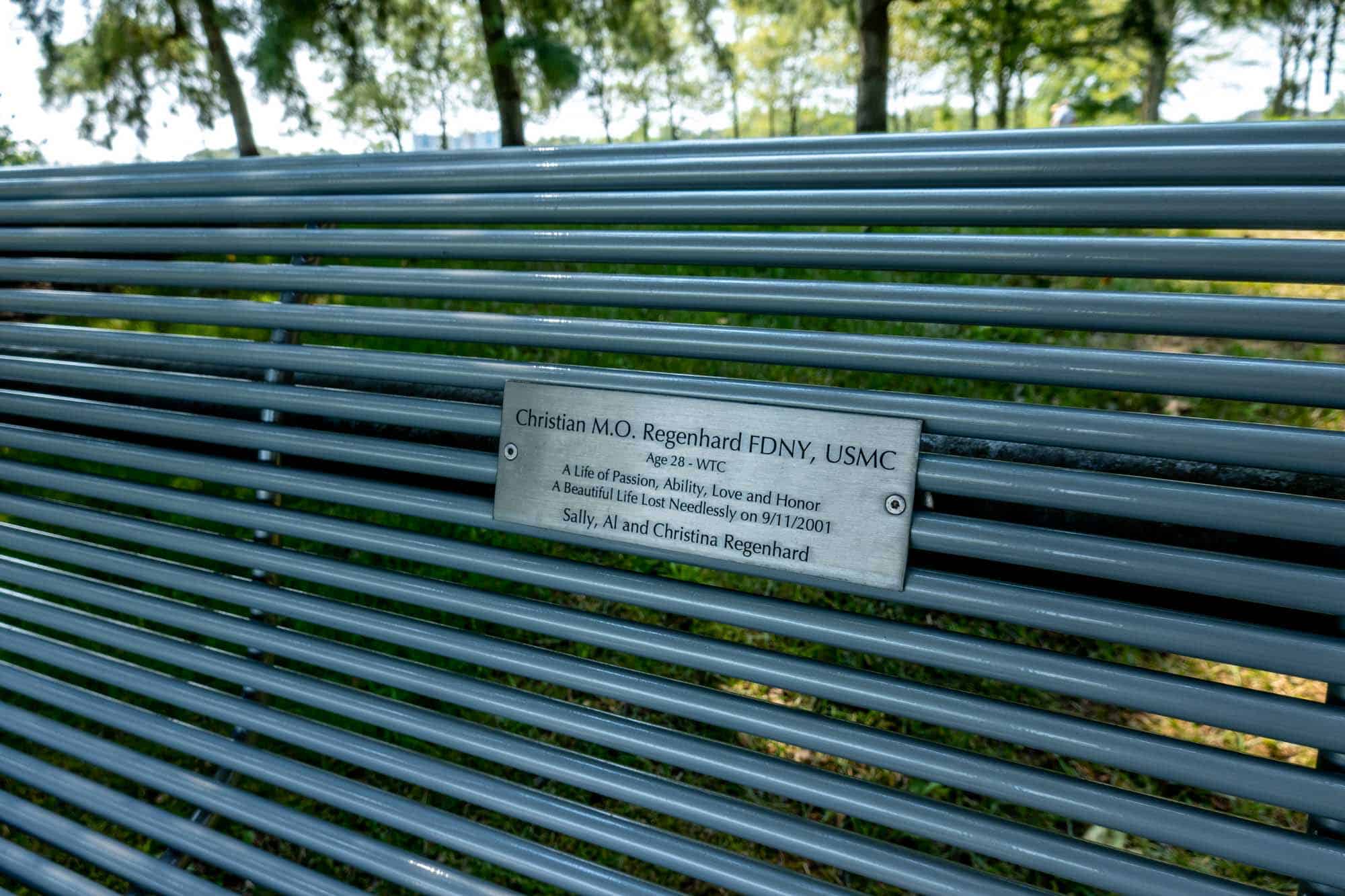 Bench with a dedication plaque: "Christian M.O. Regenhard FDNY, USMC. Age 28 - WTC. A life of passion, ability, love and honor. A beautiful life lost needlessly on 9/11/2001. Sally, Al and Christina Regenhard"