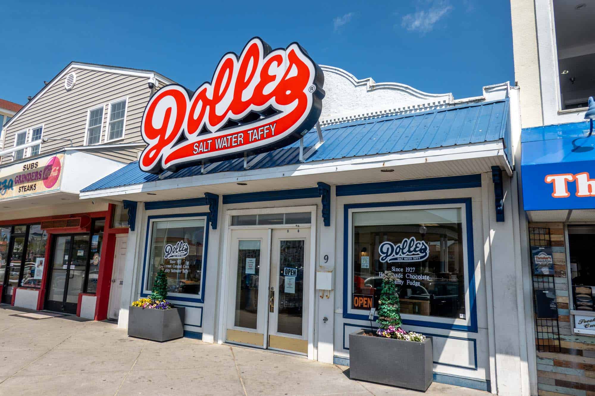 White building with blue roof and a red sign: "Dolle's Salt Water Taffy."