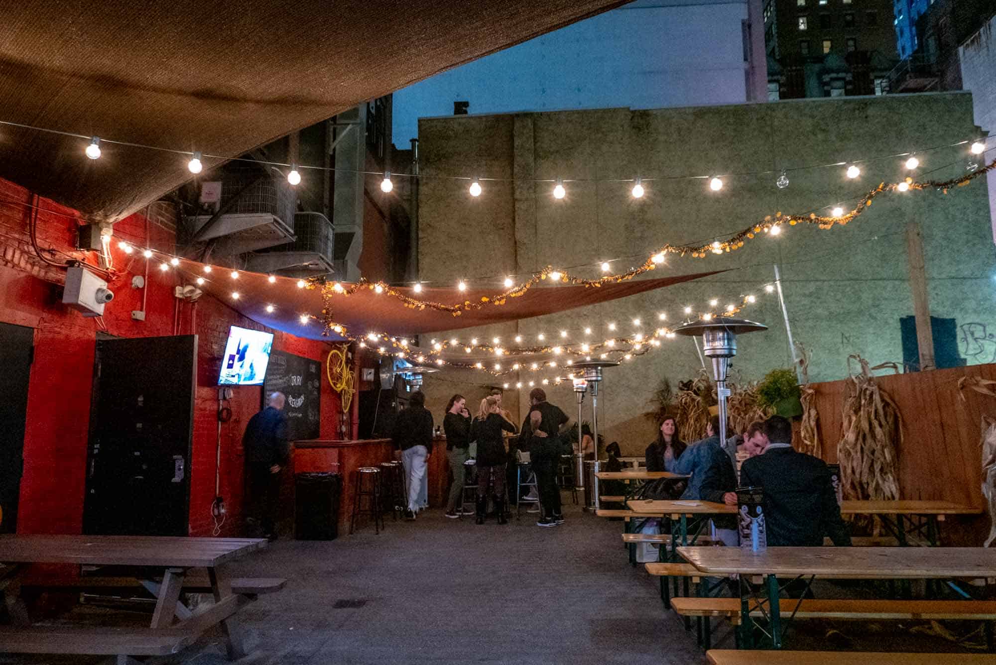 People at picnic tables in outdoor beer garden.