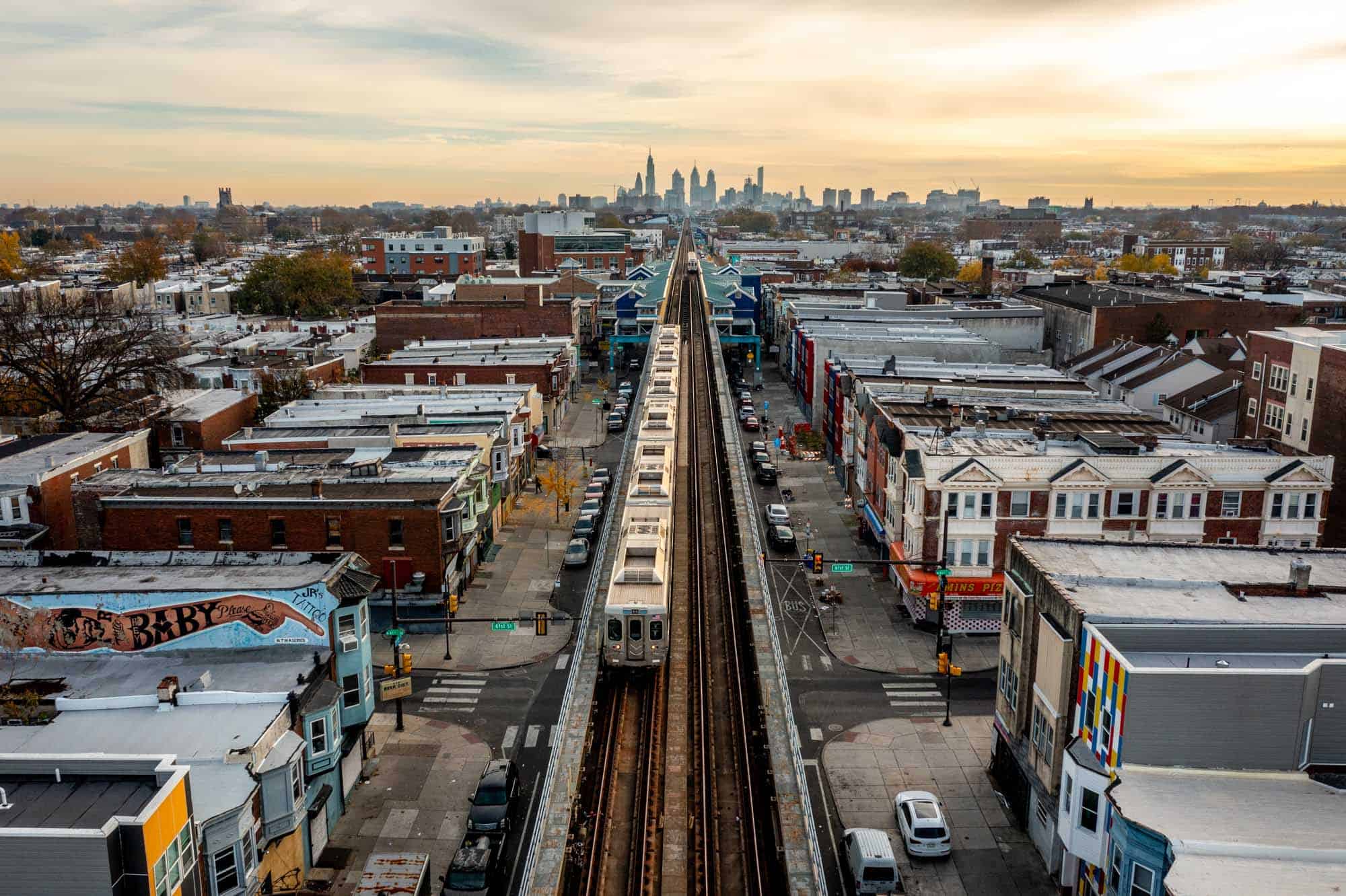 An elevated train in West Philly with the skyline in the distance.