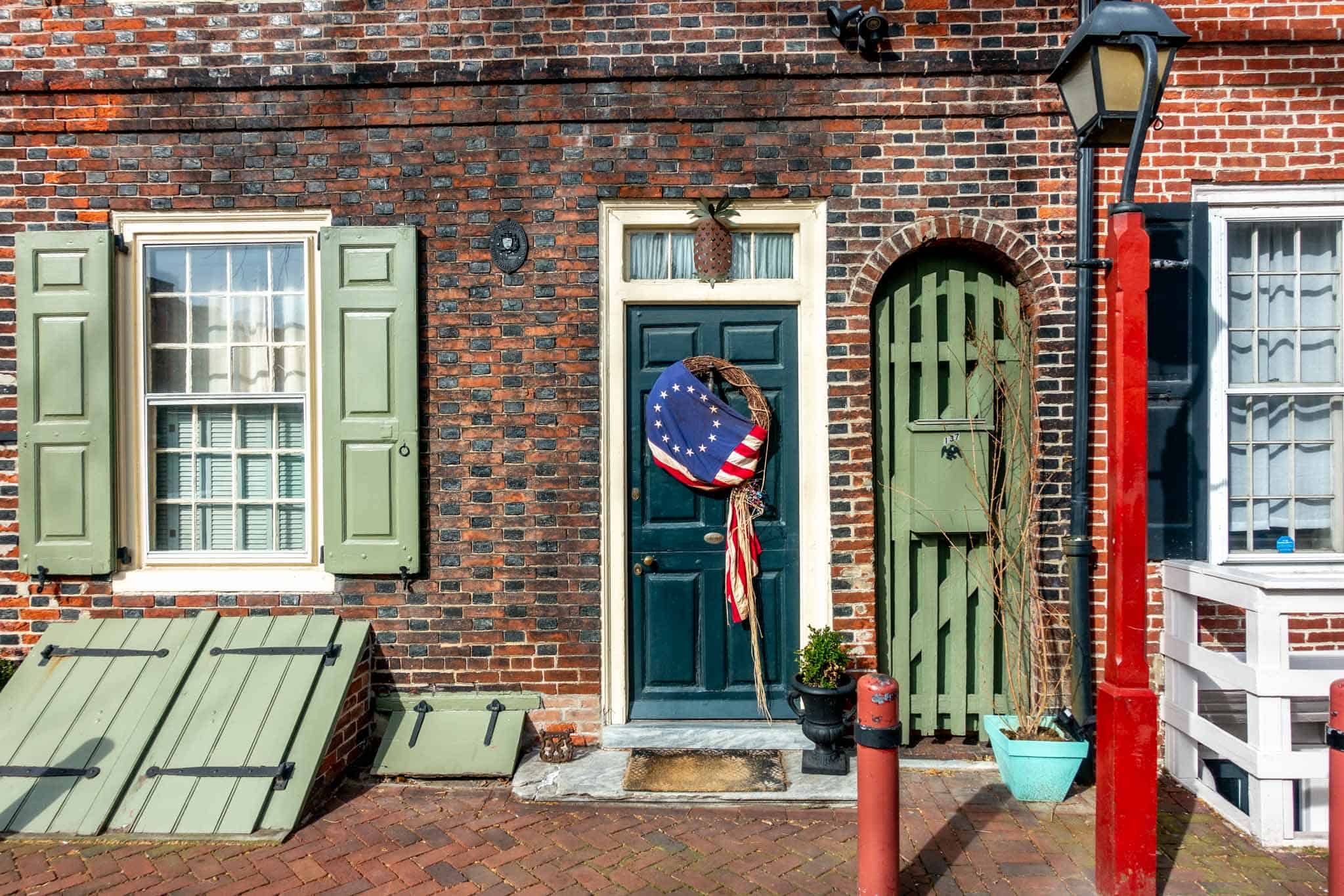 Entrance to home in Elfreth's Alley with green door, shutters, and a wreath covered with the colonial American flag