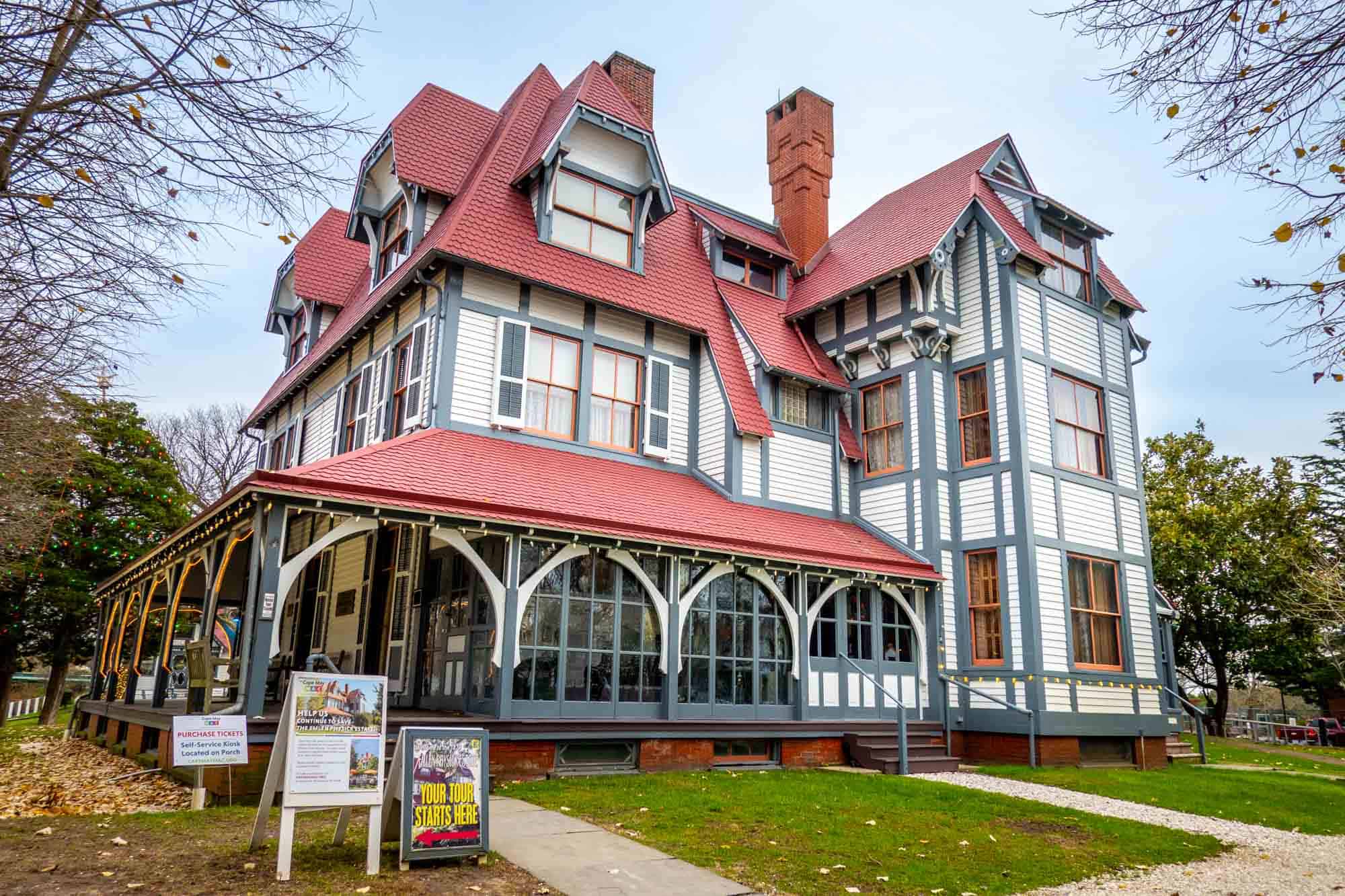 Large Victorian house with a porch and red roof.