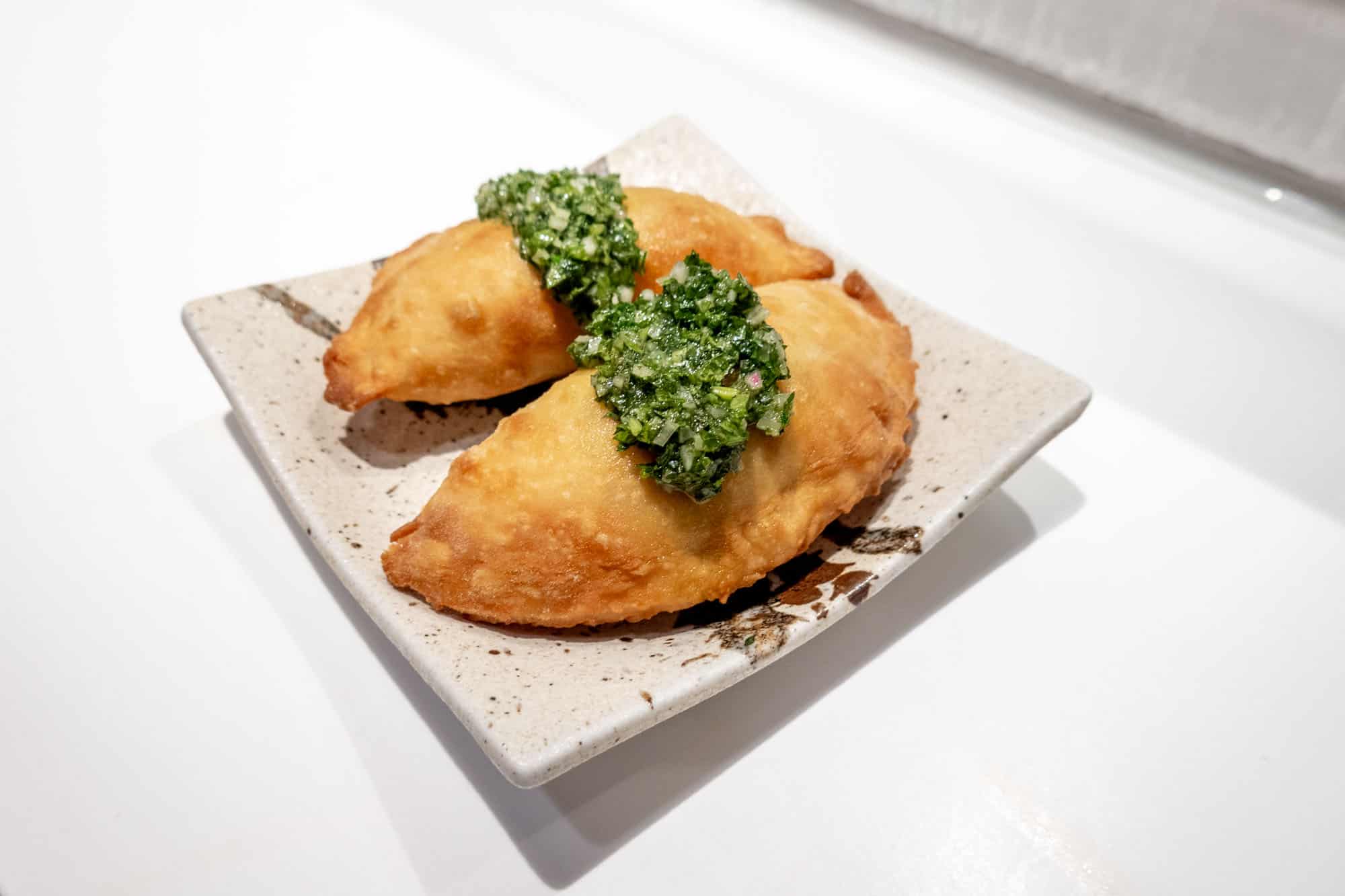 Empanadas topped with a green chimichurri sauce