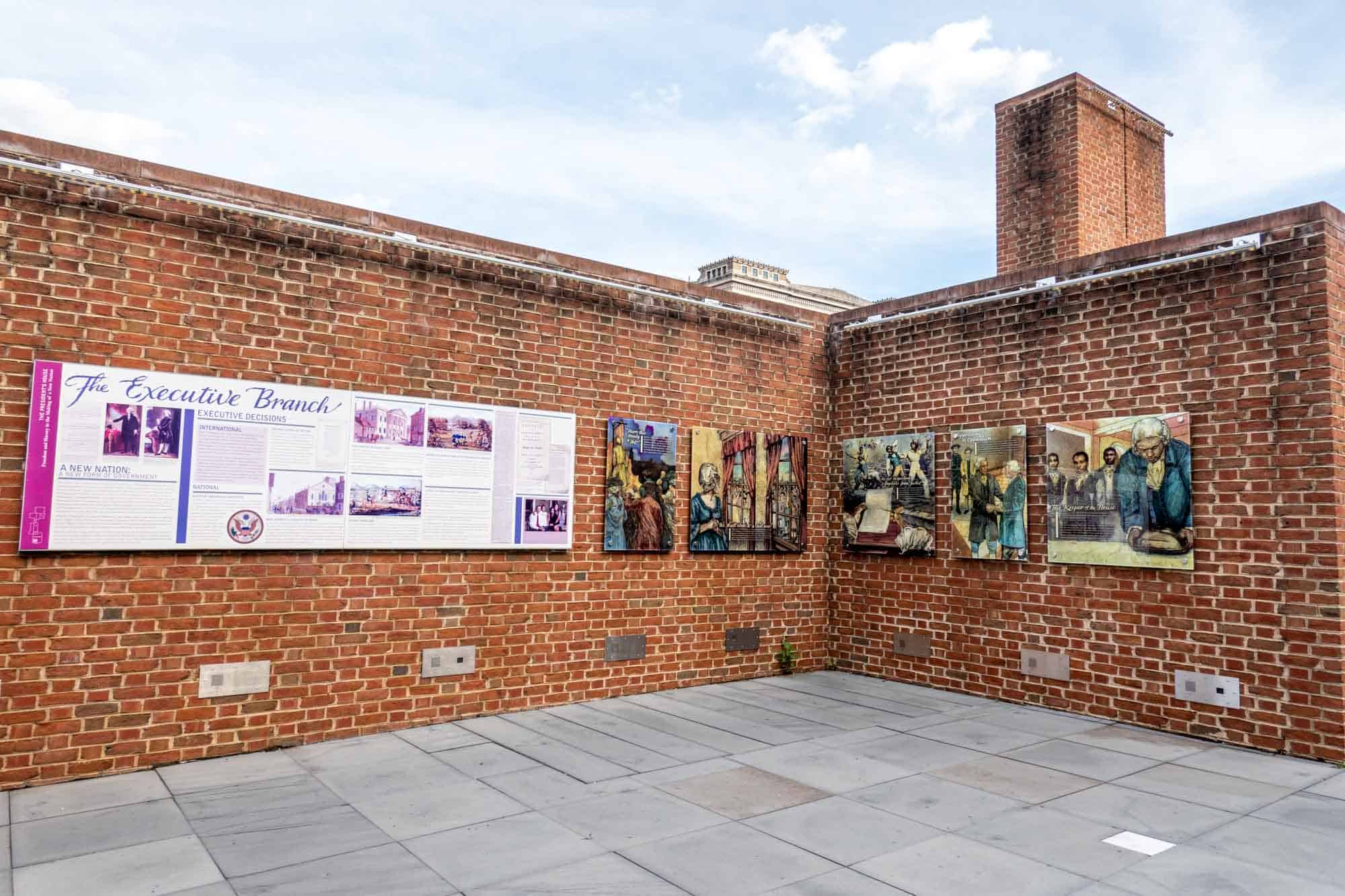 Open-air exhibit including information panels on a brick wall.