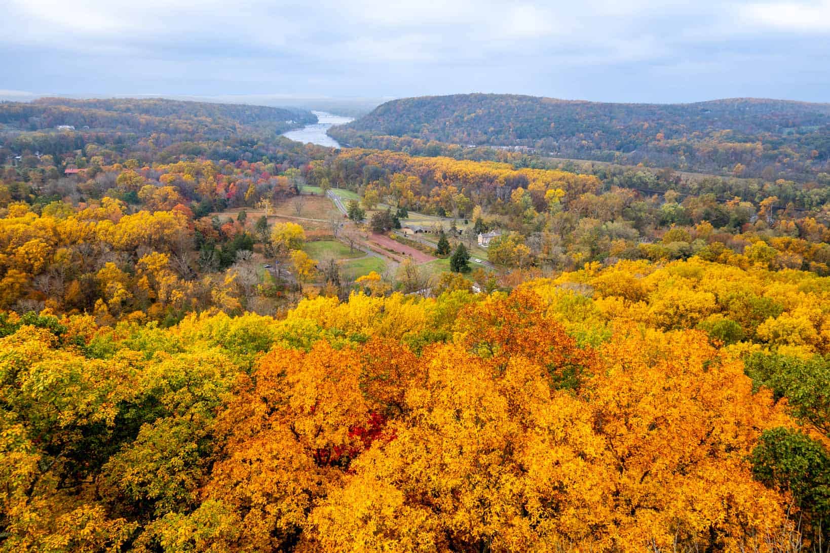 Aerial view of a landscape filled with fall foliage and a river cutting through it