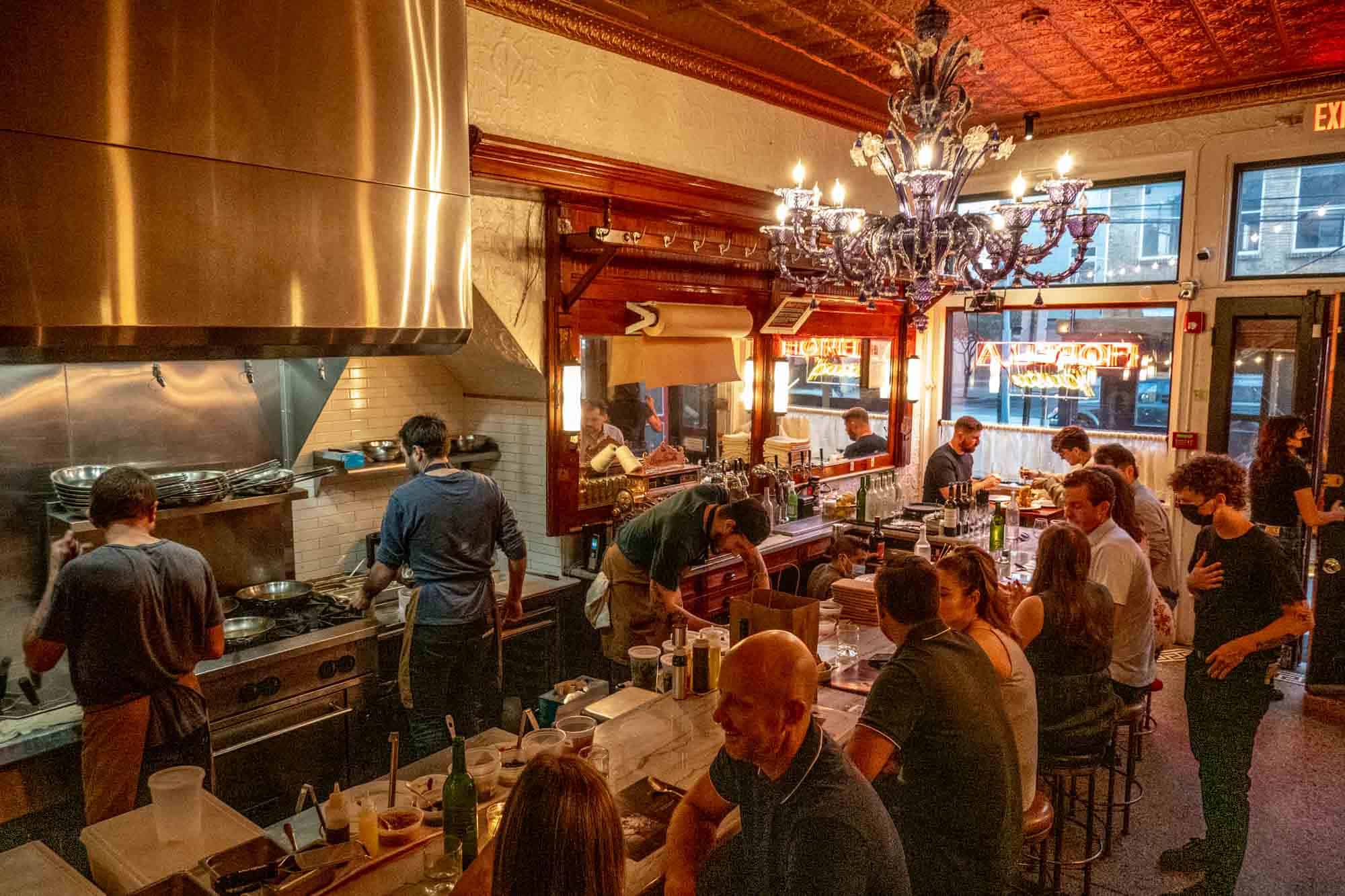 People seated at a counter in front of an open kitchen.