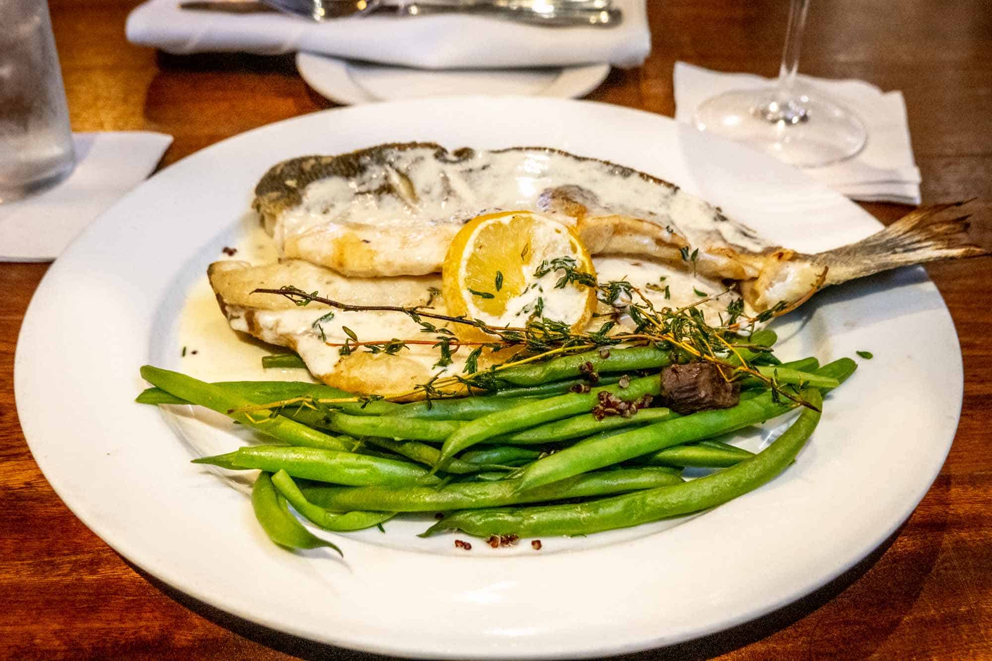 Plate with green beans and fish with a slice of lemon.