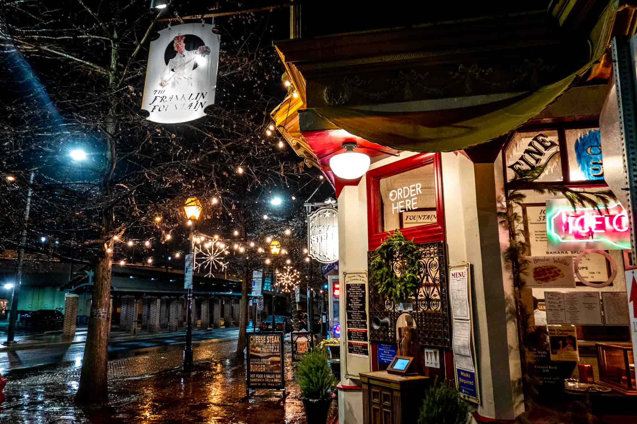 Exterior of a store with neon signs at night and a sign: "Franklin Fountain"