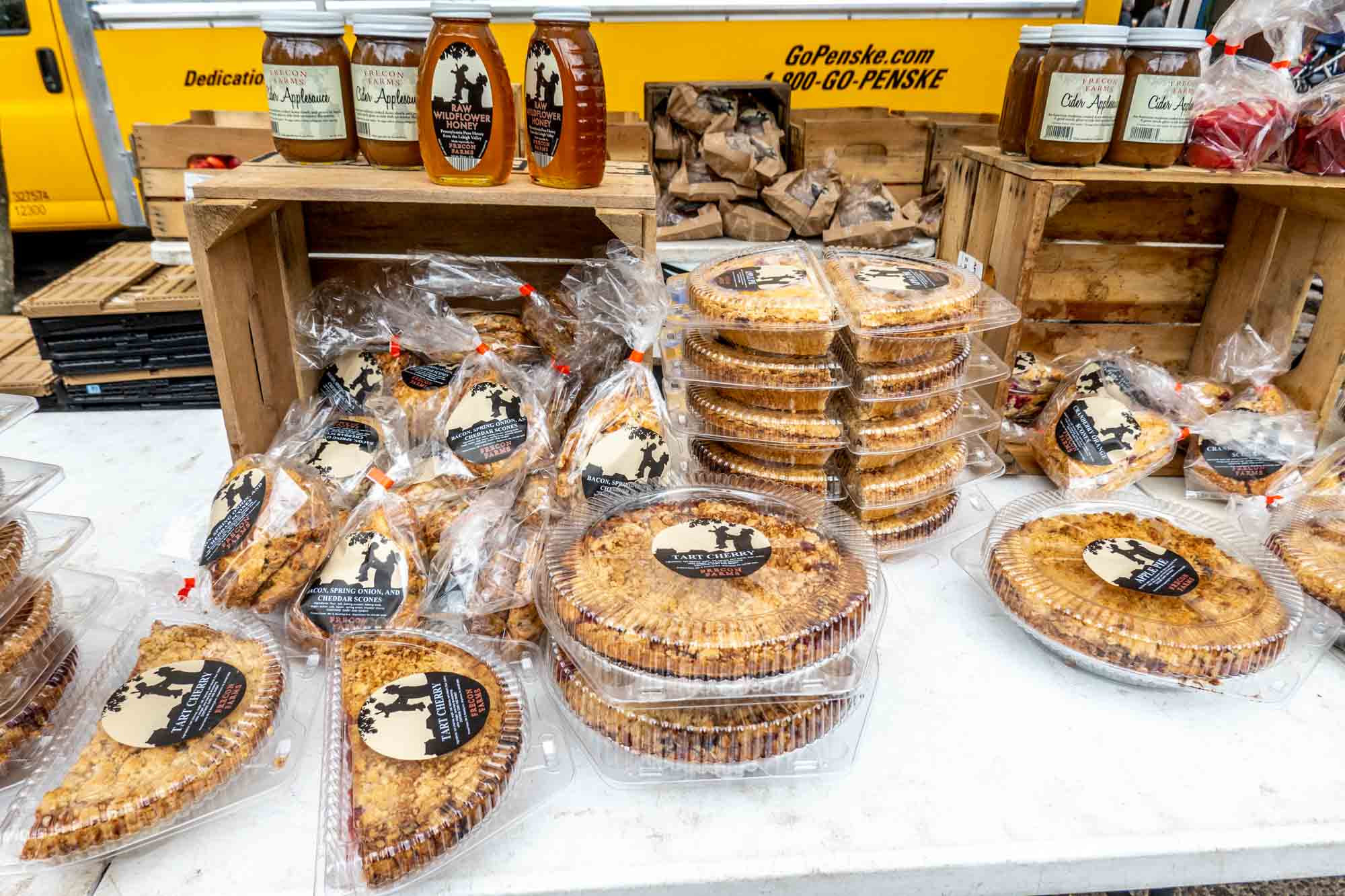 Table at farmers market with fresh pies, bottles of honey and applesauce