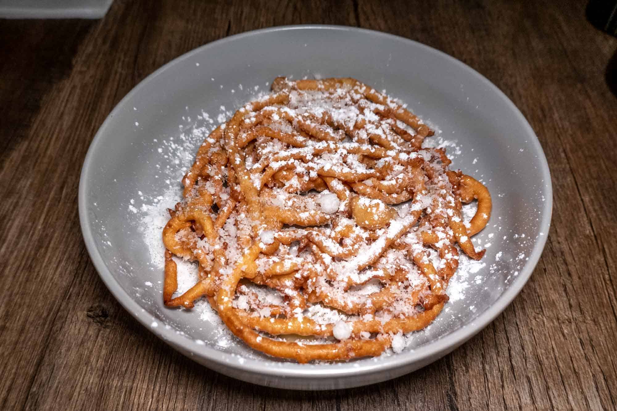 Funnel cake topped with powdered sugar and shredded coconut