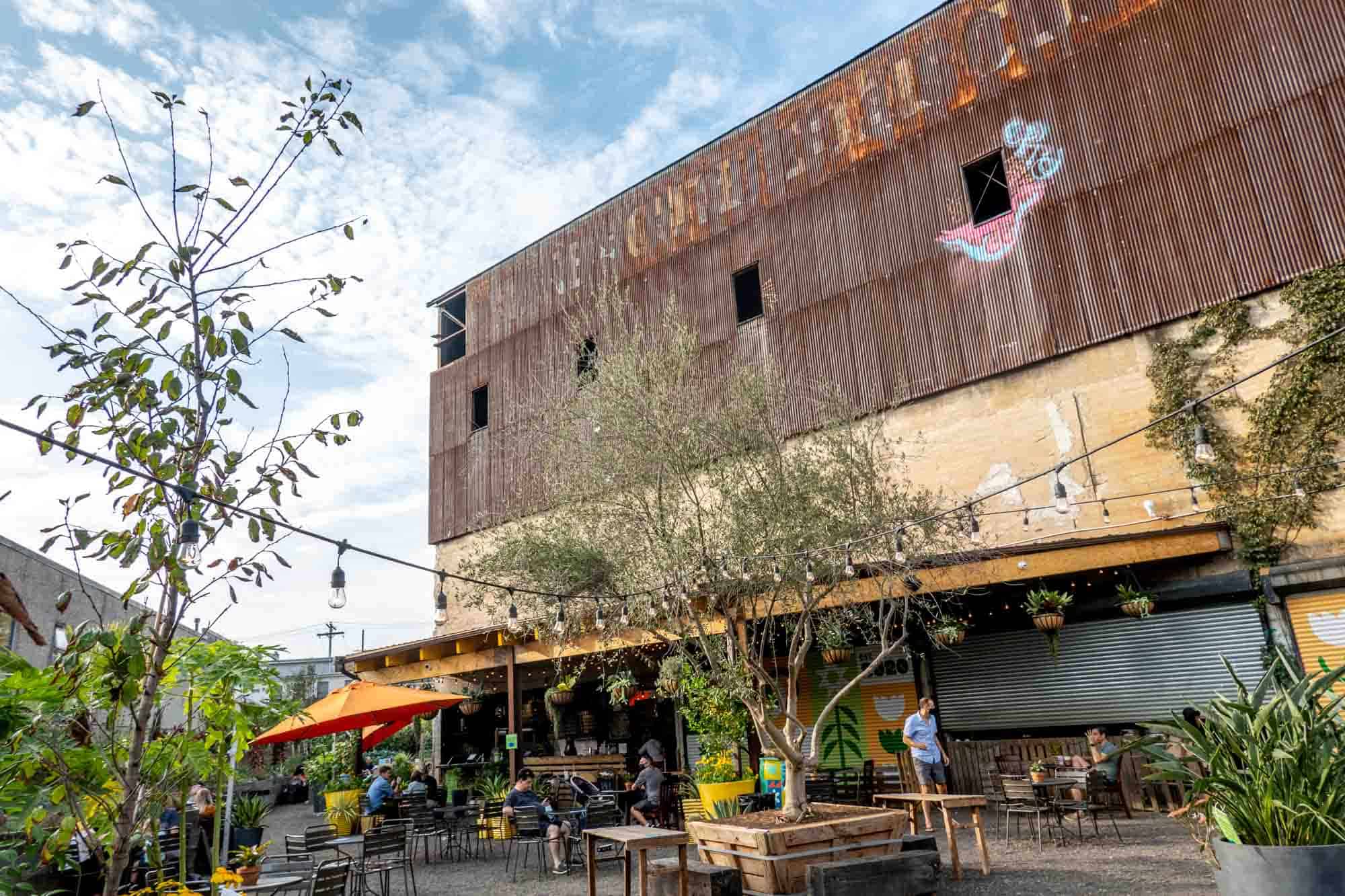 Beer garden at base of rusted, abandoned industrial building