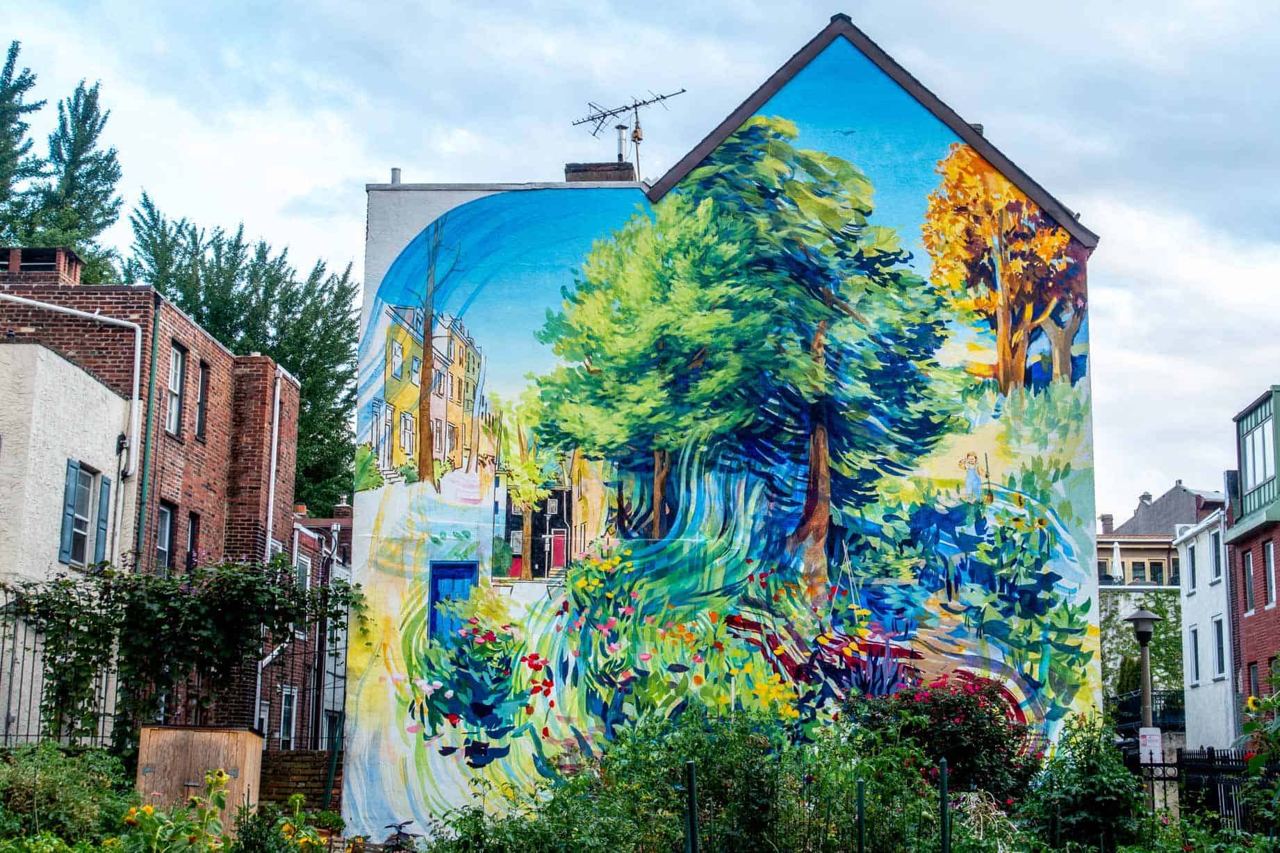 Mural on the side of a building featuring bright trees and gardens.